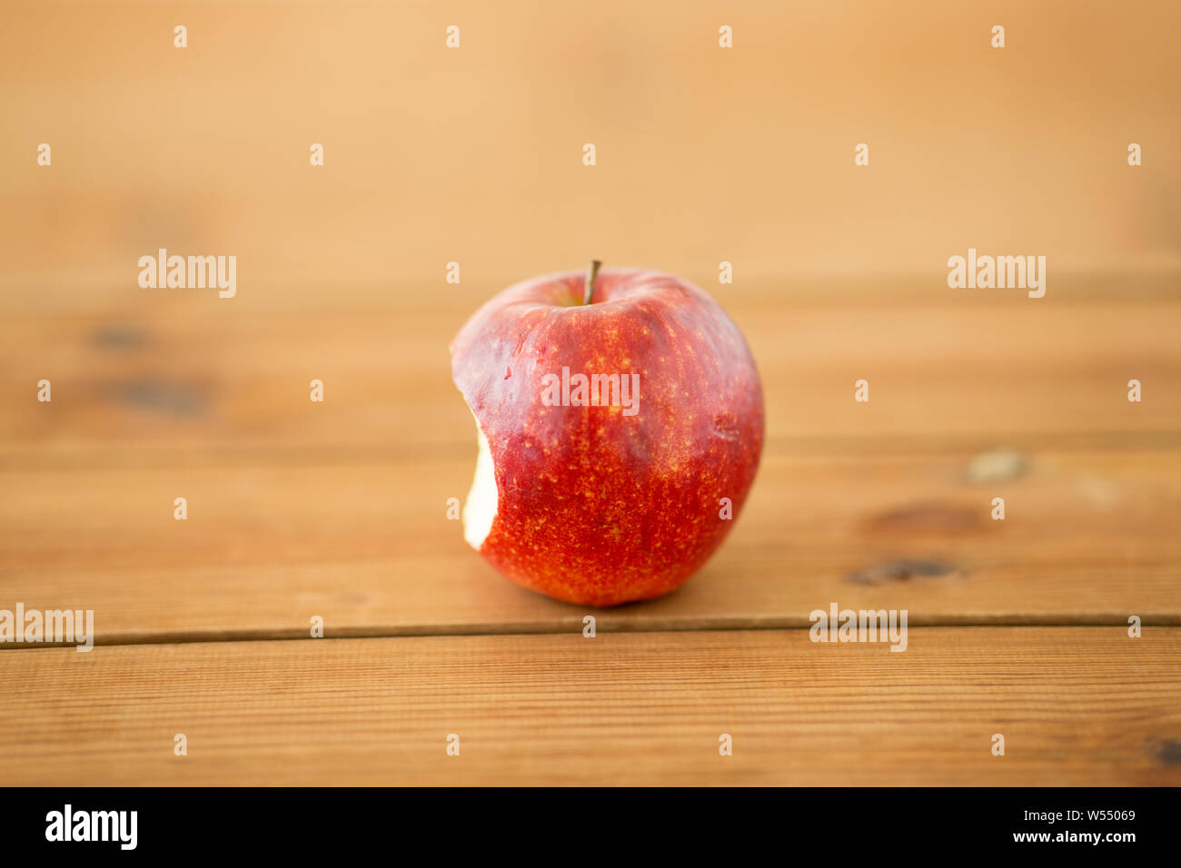 ripe red bitten apple on wooden table Stock Photo