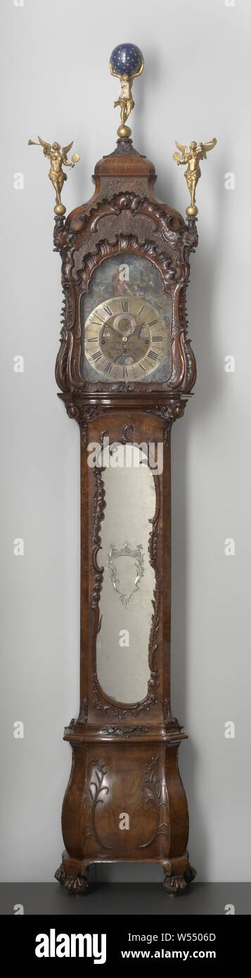 Longcase clock Floor clock, Floor clock from burr walnut on an oak core. The curved base with angled posts rests on claw feet. The front of the straight cupboard consists of a arched door with mirror with ground ornament and asymmetrical frame. The hood rests on a curved frame, has a glazed door and shows cut-away sawing. Pedestals with trumpet angels placed on the opposite corner, for atlas crown with celestial sphere. The corners of the timepiece are painted. Clock with seed beads, foliage, tendrils, branches, ornament, rocaille ornament, angels, Atlas supporting the heavens on his shoulders Stock Photo