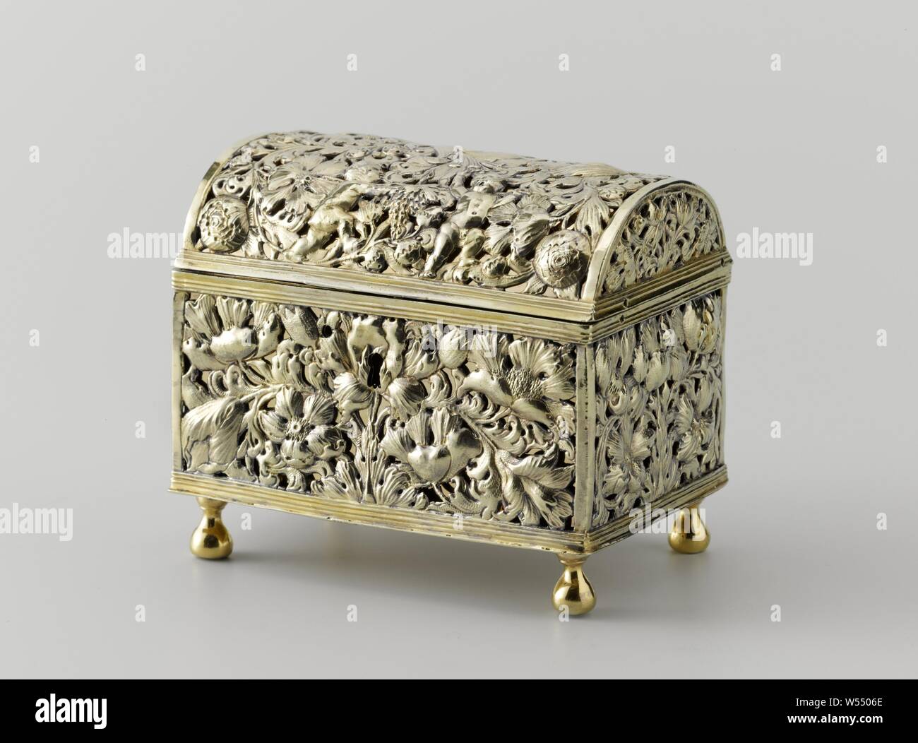 Knot chest of gold-plated silver. Walls and lid open with flower and leaf work. The rectangular box has a convex, hinged lid and rests on four balustering legs. Profiled edges run along the top and bottom of the box, and along the bottom of the lid. The walls and the lid are cut open and then embossed with a decoration of flowers and leaves. There are two dancing putti on the lid. On their shoulders they carry a branch with a bunch of grapes. At the front there is a keyhole with a round hole on either side. Probably a closing plate was originally confirmed there., flowers, ornament, Roeloff Stock Photo