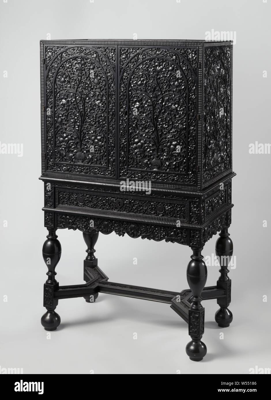 Cabinet, two-door, on base and decorated with sculpture, Ebony two-door cabinet on base, decorated with sculpture. The frame with drawer rests on vase-shaped articulated legs with houses, connected by a double Y-shaped cross and resting on bulbs. The sculpture of the doors and the sides depicts arches with small vases, from which leaf vines with flowers sprout, which meandering and curling fill the background. The curved edges, swivels and the top of the cupboard, as well as the drawer, top rail, houses and cross of the frame show slender motifs., anonymous, Coromandelkust (possibly), c. 1680 Stock Photo