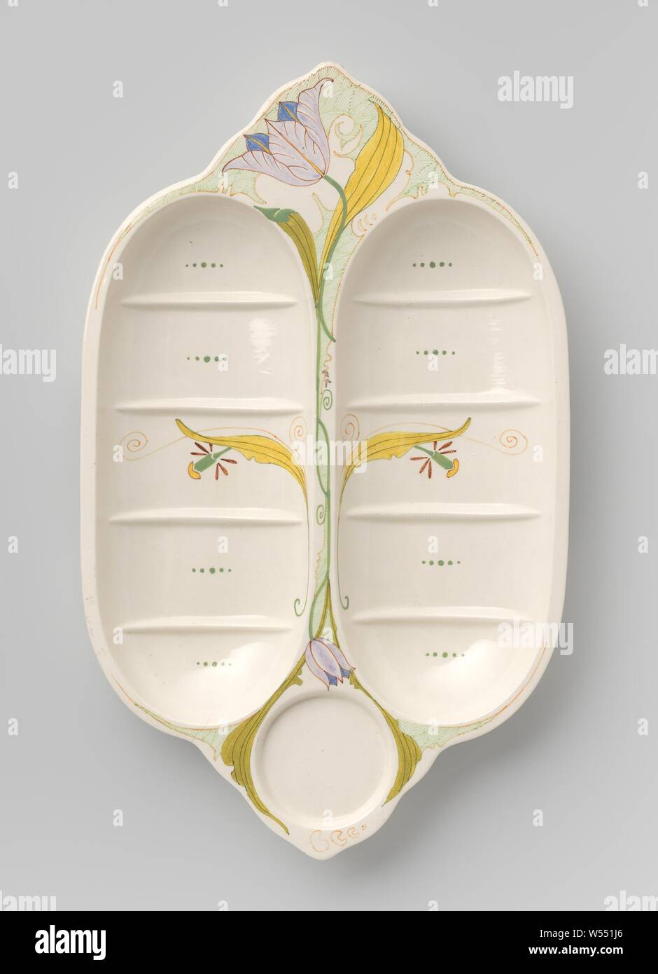 Bowl, divided into compartments, decorated with an open and a closed tulip, Bowl of earthenware, consisting of two long oval side-by-side trays on six supports. The oval trays are divided into five sections by ribs. Between the trays at one end there is a round recessed portion, on the other side a scalloped flat portion, which is decorated with an open tulip on a long stem that runs between the trays and shows a closed tulip at the other end. In the middle of the bins, a yellow leaf with a (flowered) flower. The colors are yellow, light and dark green, red, purple and blue., N.V Stock Photo