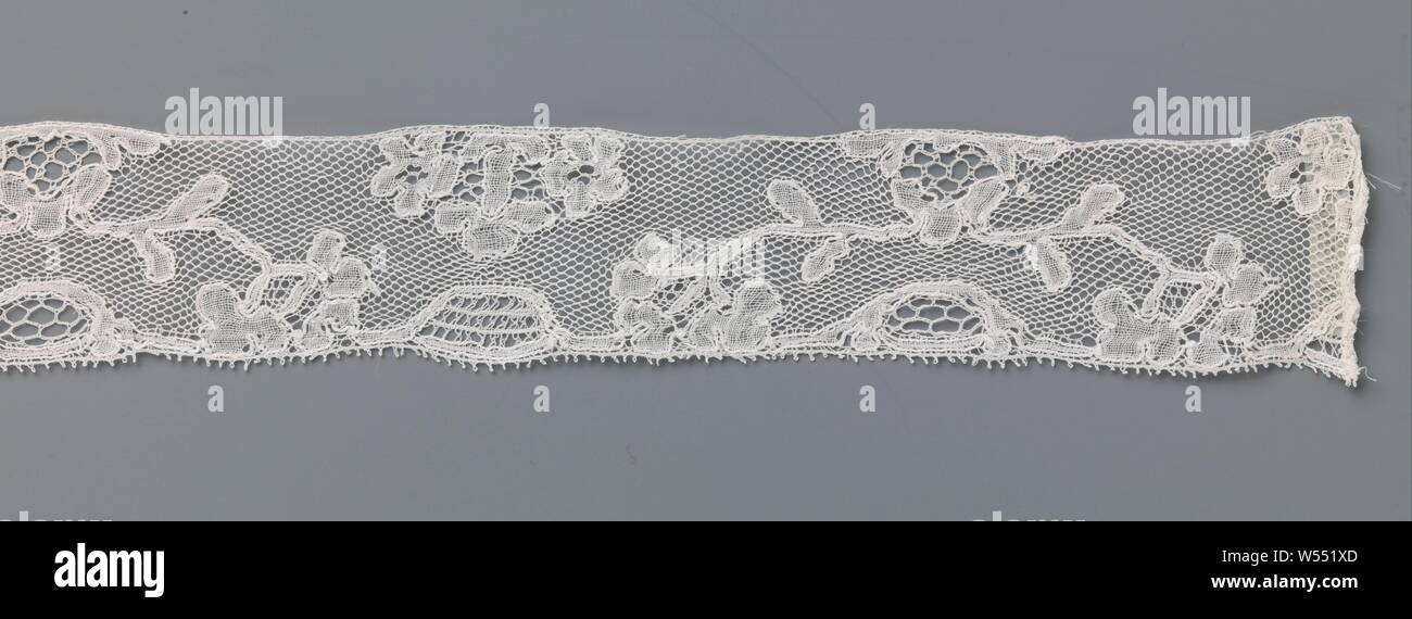 Strip of spool lace with a bow of branches from a triangular cartouche, Strip of natural spool of lace: Mechelen lace. The pattern consists of an arc formed by two branches from a triangular cartouche along the top of the strip. In the middle below the arch is a pointed oval-shaped cartouche along the underside of the strip. This composition is interspersed with a composite flower that rests against the top and underneath a trapezoidal cartouche placed against the bottom. The motifs are connected by a fine mesh soil. The motifs are made in linen with thicker and shiny contour threads. A few Stock Photo