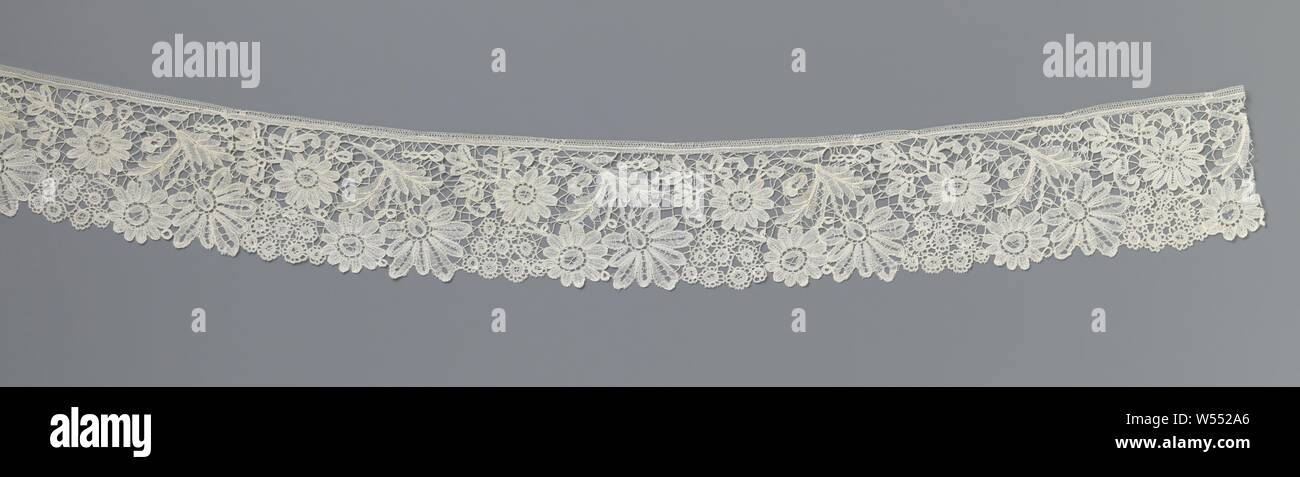 Strip of bobbin lace with two daisies and a flower in addition to a hanging flower with nine lobes, Strip of natural-colored bobbin lace: fine Bruges flower arrangements. The repeating pattern consists of a flower with nine elongated lobes and a small oval flower heart that hangs down from the top to the bottom of the strip on a curved stem. Between the successive hanging flowers are two daisies diagonally below each other and a flower with circular flowers. The motifs are connected to each other by a pictured braided soil. They are made in loosely worked linen with cutouts and are for Stock Photo