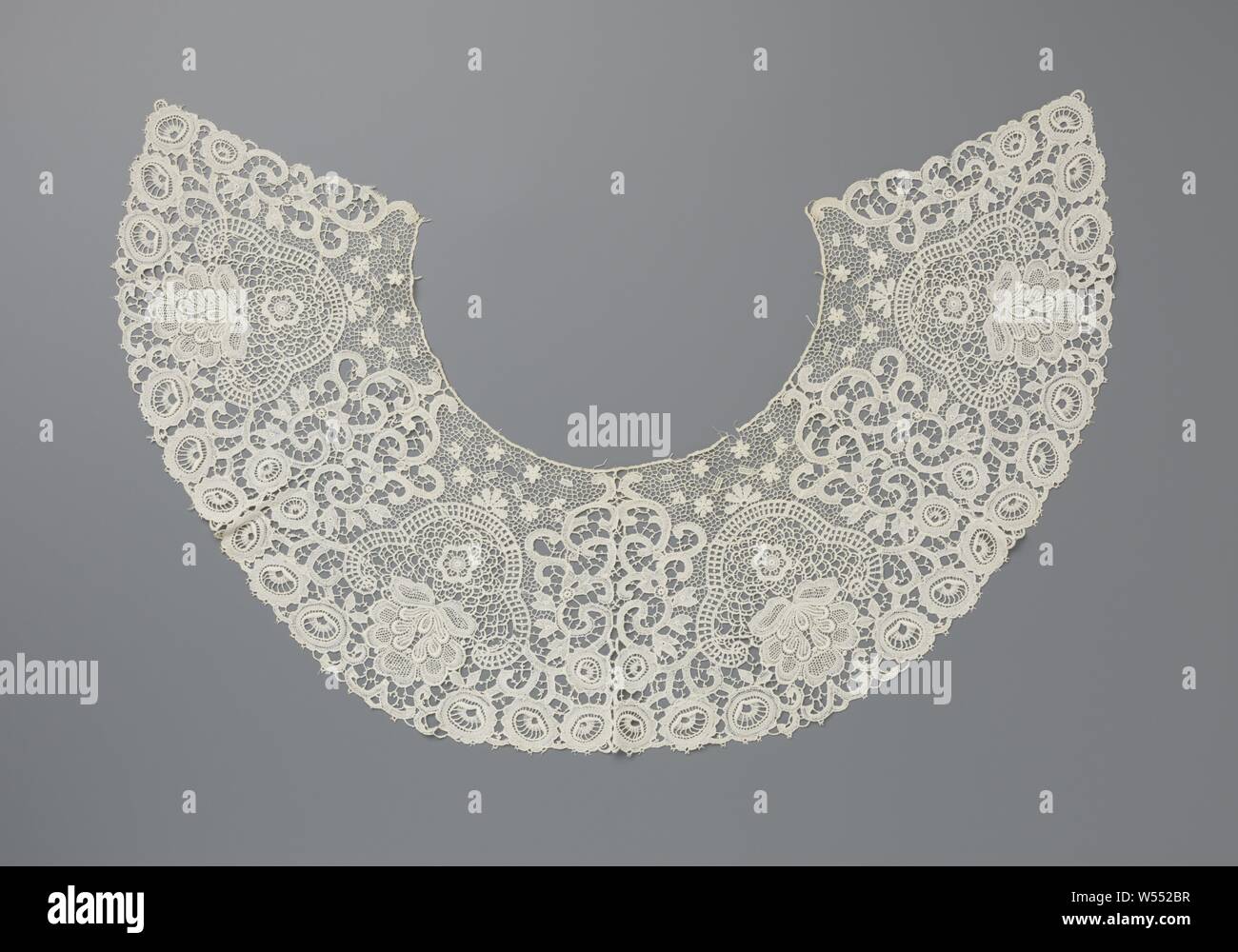 Machined lace collar with four inverted flower pots with fan flower, Natural colored machined lace collar: etching lace, imitation of needle lace. The wide collar forms almost two-thirds of a circle. Symmetrical pattern with four inverted flower pots with a large fan-shaped flower on two leaves. A pattern of curly tendrils has been placed between the successive flower pots, which end along the outer edge with a row of a total of six oval flowers. The tendrils are connected to each other by a barbed ground. On the inside of the collar the motifs are connected to each other by a finer mesh, Stock Photo