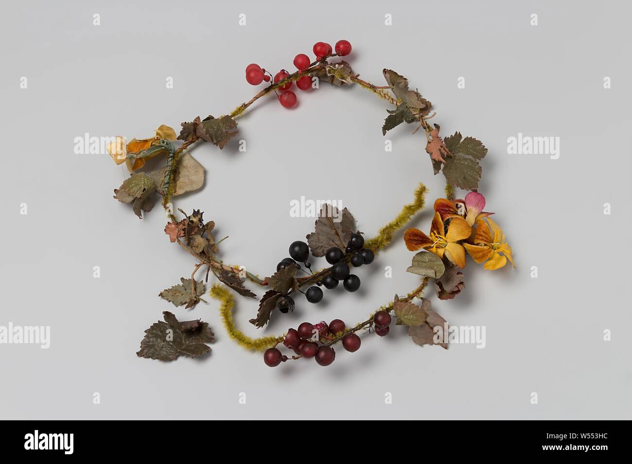 Wreath with yellow flowers, red and black berries and green leaf, Wreath with plastic velvet yellow flowers, plastic red and black berries and green leaf of synthetic silk, branch wrapped with iron wire. Hat garment or corsage., anonymous, Netherlands (possibly), c. 1900 - c. 1910, tak, bloemen, bessen, bladen, l 55 cm × h 3 cm × w 6 cm Stock Photo