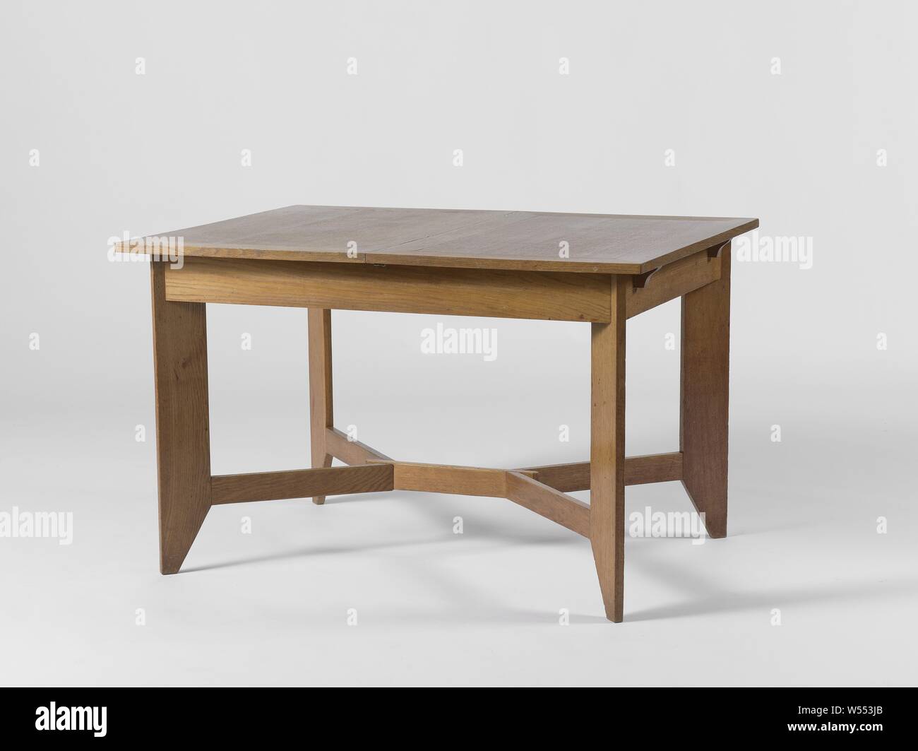 Table resting on four angled legs, Oak and beech table resting on four rectangular legs angled. The legs have a beveled corner on the underside and are mutually connected at the height of this corner by means of a double Y-shaped cross. The legs are connected to each other at the top by broad lines with a frame of horizontal and vertical lines on which the tabletop rests. The table top consists of two extendable parts., Hendrik Wouda, The Hague, c. 1924, oak (wood), beech (wood), h 75.5 cm × w 90.0 cm × d 120.0 cm Stock Photo