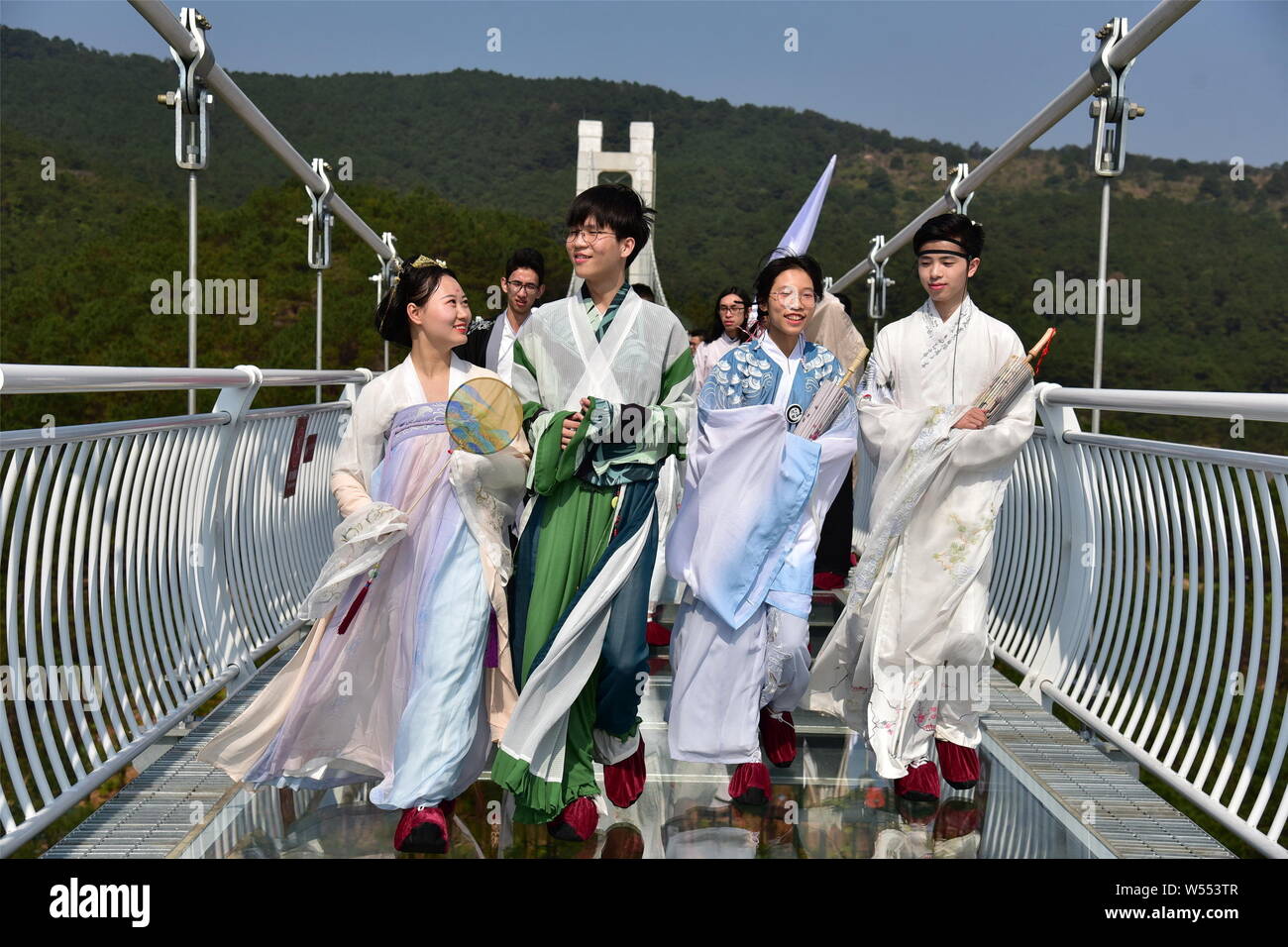 Models dressed in Hanfu or traditional Chinese costume pose on a glass ...