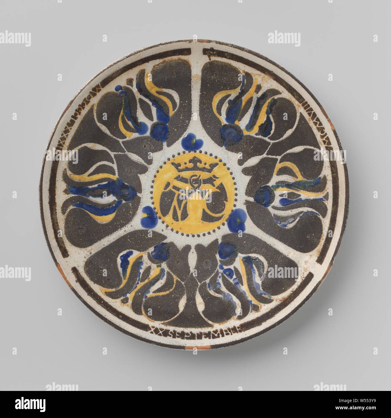 Wall plate for the 25-year wedding of J.R. Tutein Nolthenius and M.A. Cordes, Pottery plate, serving the 25-year wedding of J.R. Tutein Nolthenius and M.A. Cordes. The abstracted flower (?) Decor is executed in brown (saved in the white glaze) and in yellow and blue on the glaze, in the middle a round yellow field with a double shield under a crown, again in brown and saved in the white glaze, with the letters N and C in yellow. On the border in white on brown: MDCCCLXXXIII (left) and MCMVIII (right) and at the bottom XX September., Carel Adolph Lion Cachet, Delft, 1908, earthenware, h 3.3 cm Stock Photo