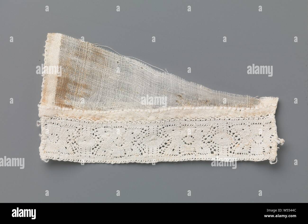 Strip of bobbin lace with stylized flower between two vertical lines and ovals on a triangular fragment of linen batist, Strip of natural-colored bobbin lace, old Flemish lace or Dutch bobbin lace. The strip is attached to a triangular piece of linen batiste. The lace has a pattern that consists of vertical straight lines, with a stylized flower in between. On the center line, the flower is flanked left and right by a horizontal pointed oval, which always crosses the vertical line. The motifs are made of linen with cutouts, there is hardly any ground, the motifs are connected by very short Stock Photo