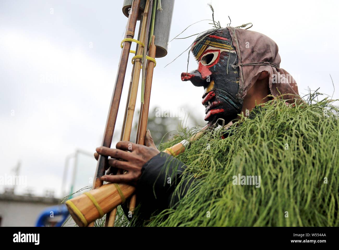 Chinese people of Miao ethnic group wearing masks and grassy cloaks dress up as the god to bring good luck to villagers during the Manggao Festival in Stock Photo