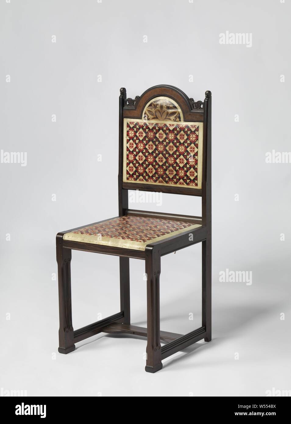 Chair covered with batik parchment in red, white and black diamond motif, Chair made of coromandel wood resting on four legs. The front and rear legs are connected to each other by means of intermediate lines, which are connected to each other in the middle by a panel. The hind legs merge with the back posts that are crowned by monkey heads. The backrest is open at the bottom and closed at the top. The closed part consists of a panel that protrudes in the middle at the top in a semicircular shape with panels cut away on both sides that connect the semicircular shape to the back posts. Stock Photo