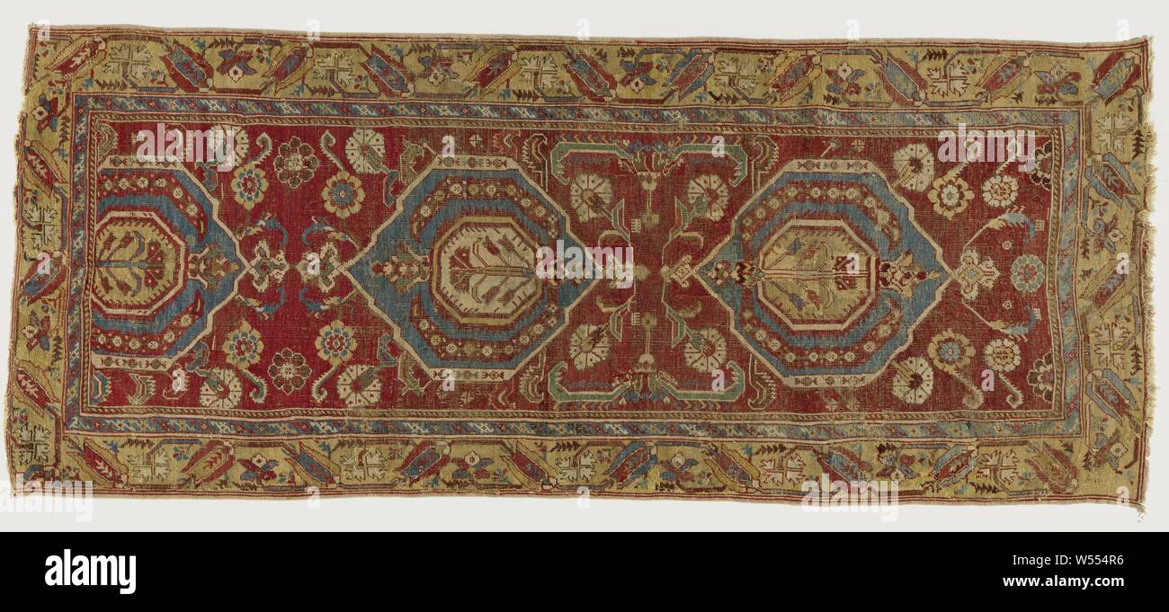 Oriental carpet, medallion rug. In the midfield are two and a half hexagons on a wine red ground. In each case an octagon with carnation. On the field carnations and rosettes. Dual edge. The widest yellow ocher with tulips on tendrils. Button: Ghiordes button., Kula, 1600 - 1800, ketting en inslag, h 254 cm × w 105 cm Stock Photo