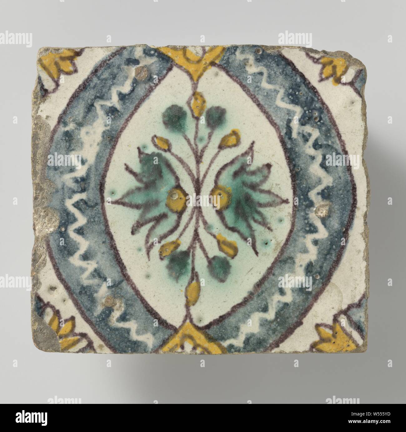 Tile, Tile of earthenware, painted in blue, green, yellow and manganese, blue oval with symmetrical leaf motif. Parts of rosettes in the corners., anonymous, Spain, 1700 - 1800, earthenware, h 11 cm × w 12 cm × t 2.3 cm Stock Photo