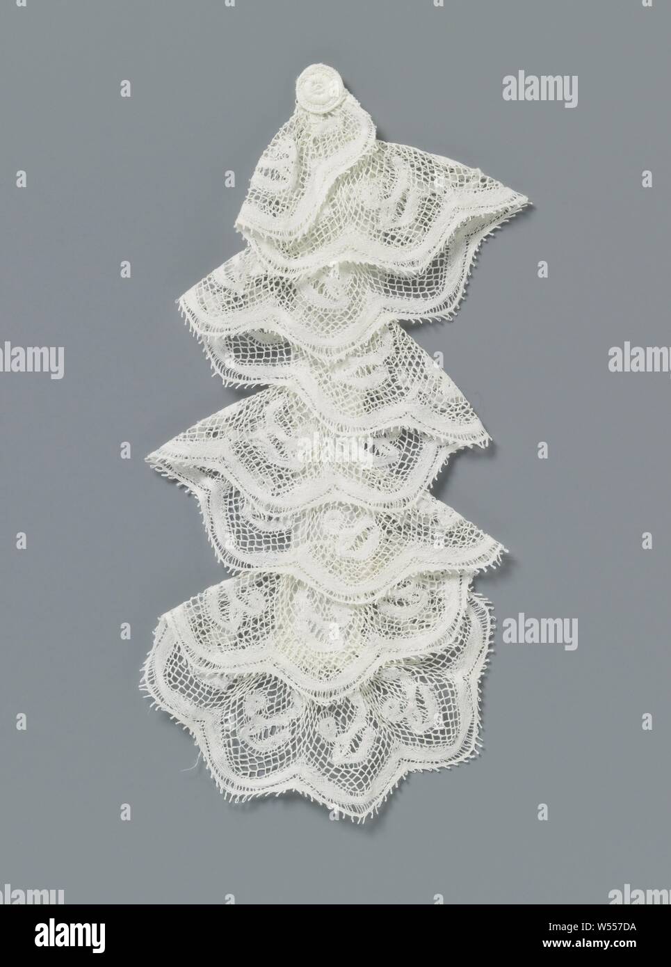 Jabot from machine-side with drop-shaped leaf and round flower, Jabot from natural-colored machine side: machine Valenciennes lace. A border strip is sewn zigzag-wise on a standing band, so that the jabot falls back and forth seven times. A cut-out embroidery rose is placed at the top. The repeating pattern consists of a hanging, drop-shaped leaf with a round flower on a short bent stem. The motifs are connected by a machine-driven Valenciennes ground with square mesh. A semicircular shell is formed around each bottom along the underside of the strip, whereby the mesh becomes a band. The top Stock Photo