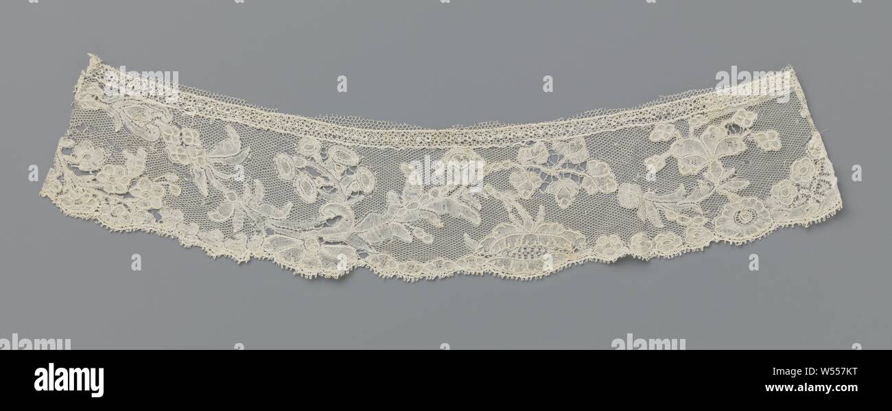 Strip of bobbin lace with pearl necklace in composite tendril, Natural Brussels-colored bobbin lace. The pattern consists of a wavy branch, which is composed of all kinds of leaves, a heart-shaped flower, a bunch of oval flowers, a pearl necklace and at the end a carnation from which four-leaf clover springs. The branch partly cuts the pattern along the underside of the strip, which consists of, among other things, a branch of forget-me-nots, an oval-shaped cartouche and concatenated leaves and rosette flowers. The motifs are connected to each other by a fine mesh soil, a drizzle soil. Stock Photo