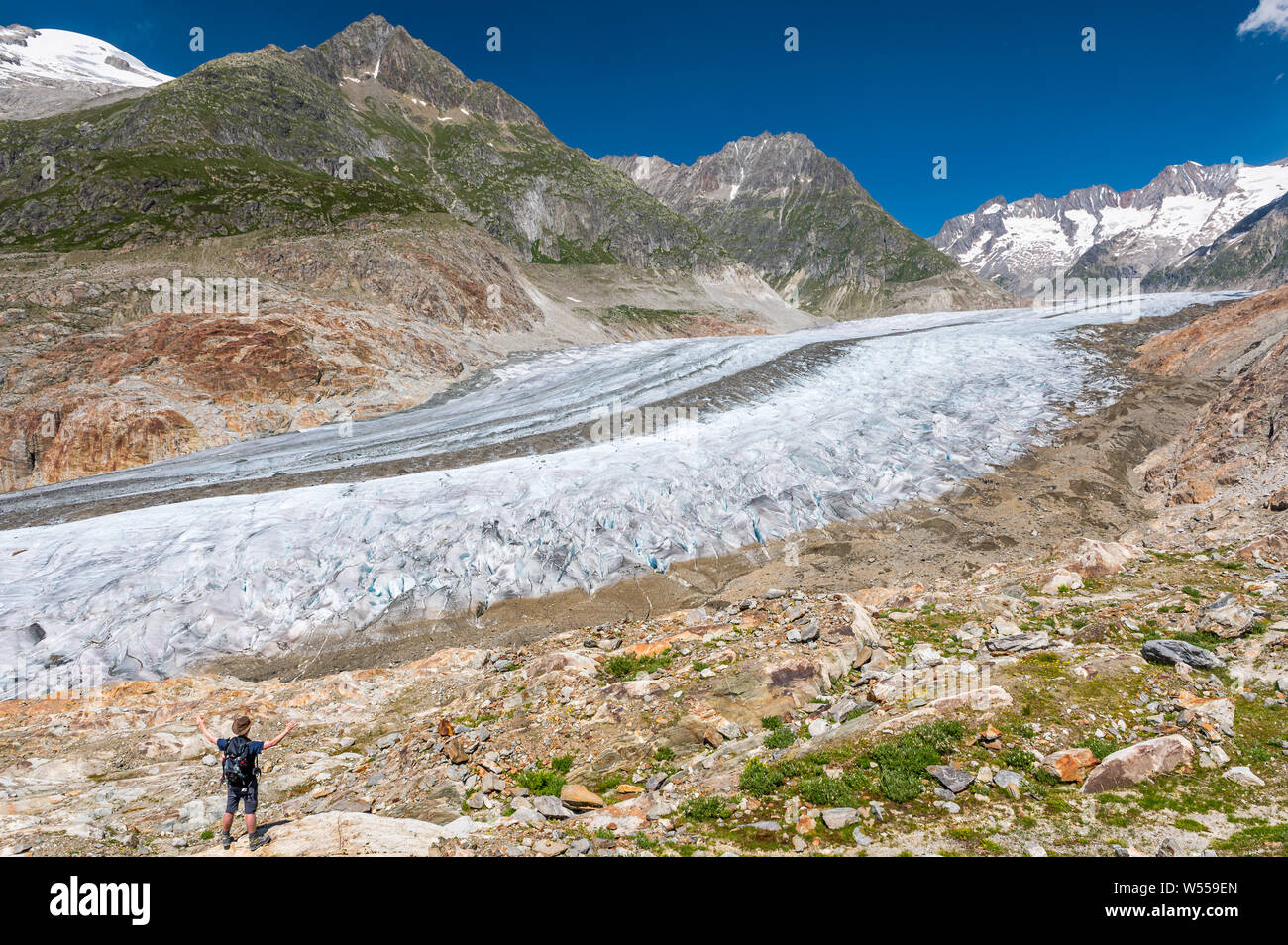 hiker with outstreched arms in front of the mighty Aletschgletscher Stock Photo