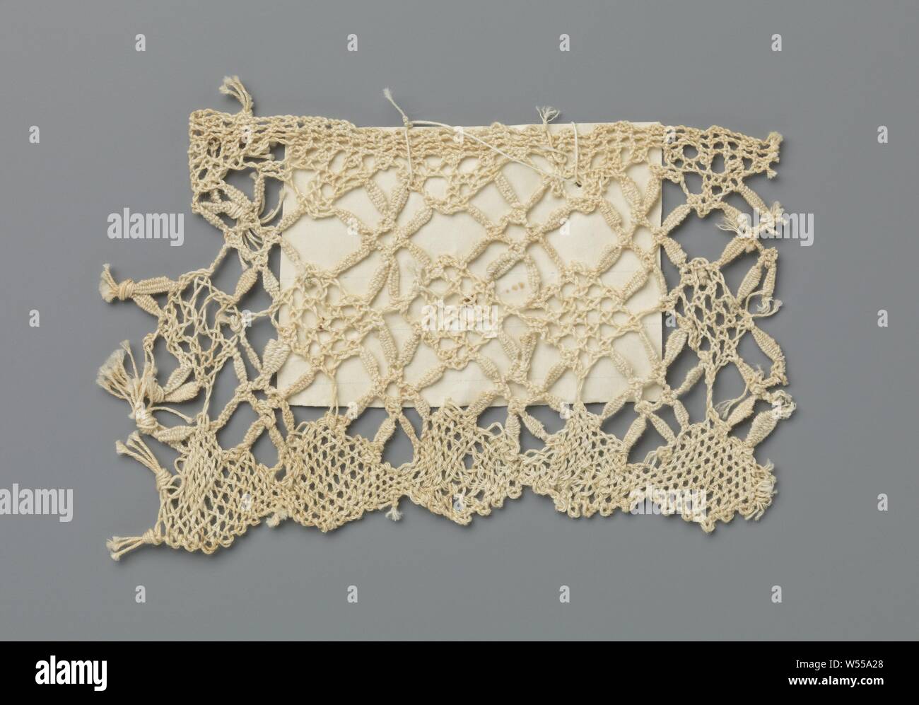 Strip of bobbin lace with diamonds Padang not Sadiah, Strip of natural-colored bobbin lace, sling side. Along the underside of the strip, the pattern consists of a row of mesh strokes. Above it is a row of diamonds with a grating ground, a five-hole ground, between coarse spiders. A label is sewn onto the strip with the text: Padang not Sadiah., anonymous, c. 1917, linen (material), torchon lace, l 9.5 cm × w 6 cm Stock Photo