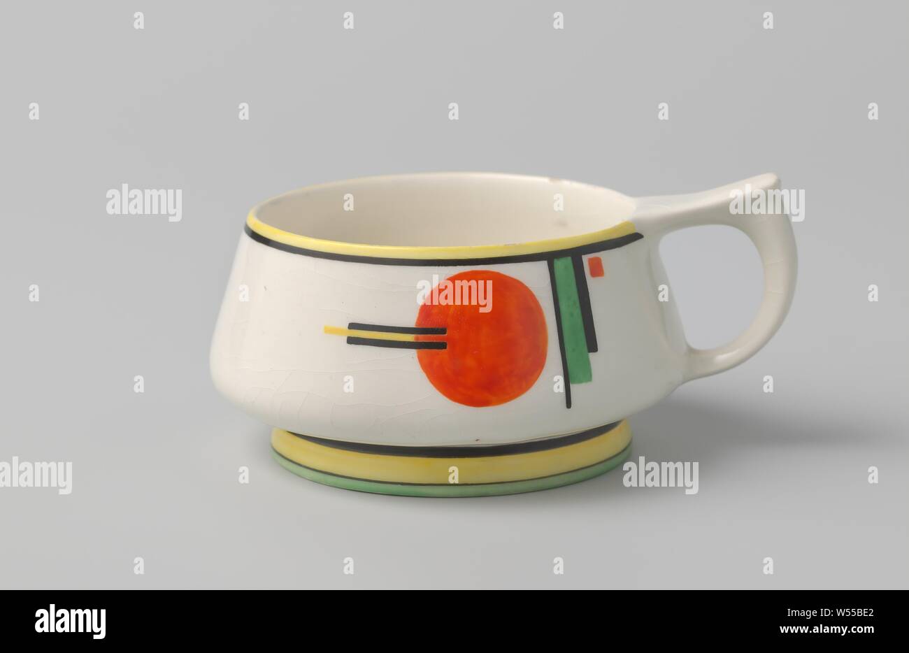 Cup with constructivist ornament, Cup of earthenware, painted in red, yellow, green and black with a constructivist ornament. On the head ao with a large round sphere. With accompanying dish (B)., Chris van der Hoef, Gouda, c. 1928, earthenware, h 5.2 cm × w 10.9 cm × d 8.9 cm Stock Photo