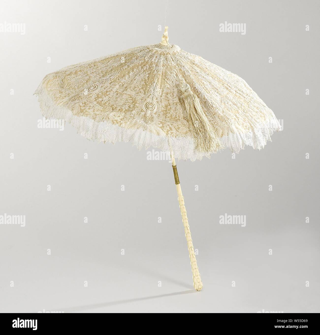 Parasol with 'point de gaze de Bruxelles' needlepoint lace on stick of, cut like link chain, ivory, Parasol with needle lace edge, 'point de gaze de Bruxelles', on an ivory silk lower deck. The lace has a pattern of medallions and heart-shaped cartouches between fields with daisies and other flowers. The deck is lined with lavender-colored ponjé silk. Eight whale whale ribs. Stick of ivory, cut with chains. Halfway through a copper slider that can be slid up, after which the stick can buckle. On top of an ivory button, in the form of two links, with a long ivory-colored brush., anonymous Stock Photo