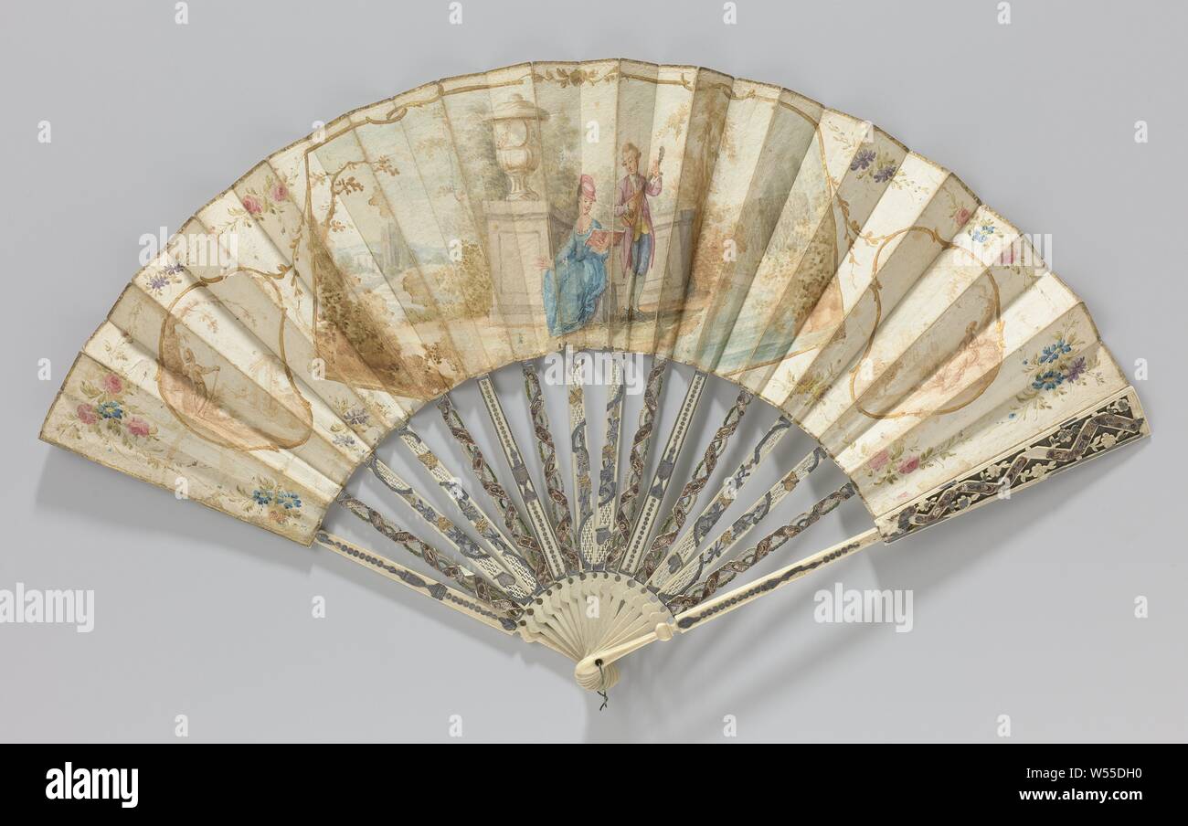 Folding fan with sheet of paper on which a watercolor painting of a couple in a landscape near a ruin, carved frame adorned with 'métal and quatre couleurs', Folding fan with sheet of paper painted in watercolor: a central cartouche with a music-making couple in a romantic landscape with ruins and mountains, on the left a cartouche with a shepherd near a classical ruin and on the right a cartouche with a shepherdess, both in sepia. Flower garlands around it. On a hill. Open frame of ajour carved ivory (?) Decorated with 'métal and quatre couleurs'. On the 16 non-contiguous legs neo-classical Stock Photo