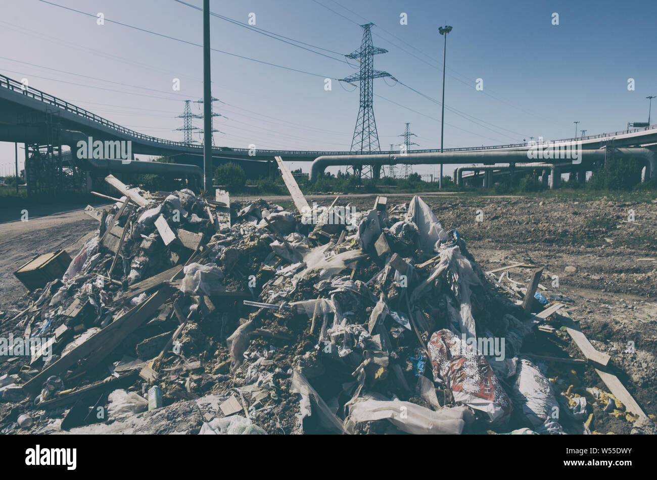 Pile of illegal dumped garbage in the city industrial zone on the background of high-voltage power lines Stock Photo