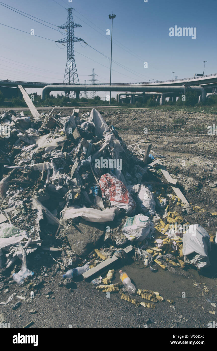 Pile of illegal dumped garbage in the city industrial zone on the background of high-voltage power lines Stock Photo