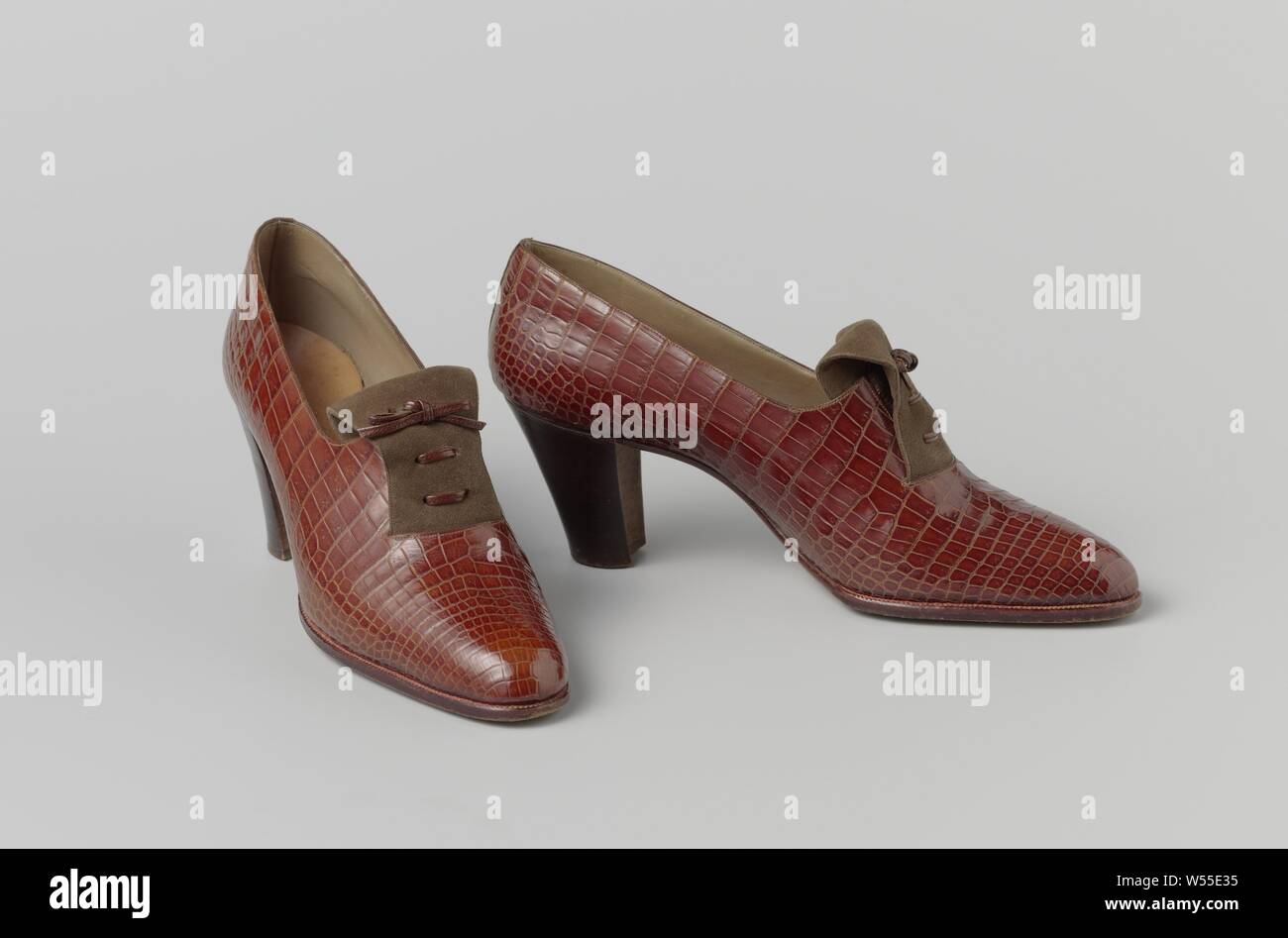 Shoe made of red-brown snakeskin with a brown suede tongue with a laced and stitched leather lace, Right shoe of a red-brown snakeskin with a brown suede tongue with a laced and stitched leather lace. Model: The slip-on with a high, straight heel (7 cm). An elastic band on the instep for easy entry. Lined with liver colored leather. Inner sole of natural leather with golden print. Leather sole and heel. Decoration: to camouflage the elastic band, a tongue of double stitched suede is applied over the instep, which comes out of a 5 cm wide semicircular cut in the front sheet and disappears into Stock Photo