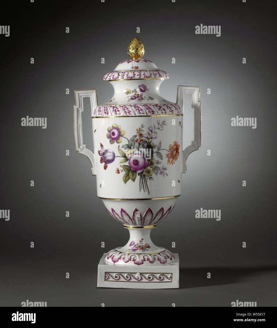 Covered vase with birds on a branch and bouquets, Porcelain covered vase on a spreading foot ending in a square base and with a cylindrical body with round shoulder and narrowing towards the foot. Spreading neck with a flat edge and high, angular ears. Painted on the glaze in blue, red, pink, green, yellow, purple, black and gold. On the belly two birds on a branch in a landscape and a bouquet of different flowers. In between scattered flowers and insects. The narrowing part to the foot with a band with modeled raised leaf motifs in relief. The shoulder and the foot with the same decoration as Stock Photo