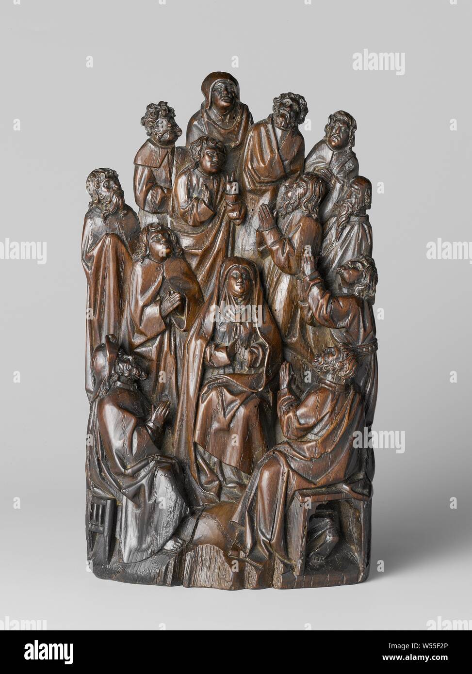 The outpouring of the Holy Spirit, Sculpture group of oak with the twelve apostles praying and looking up, grouped in a circle around Mary, the two front apostles (James on the left, possibly Peter on the right) sit on gothic stools. There are two vertical grooves in the back, (originally) possibly for fixing the group in a small retable, or for a small canopy with the dove (holy spirit), which is now missing. On the back an old label with inscription, probably in 18th century hand: This is Uijt the fire of d 'Capel in d'Calvere Street in Amsterdam arrived in year 1452, Pentecost: the Holy Stock Photo