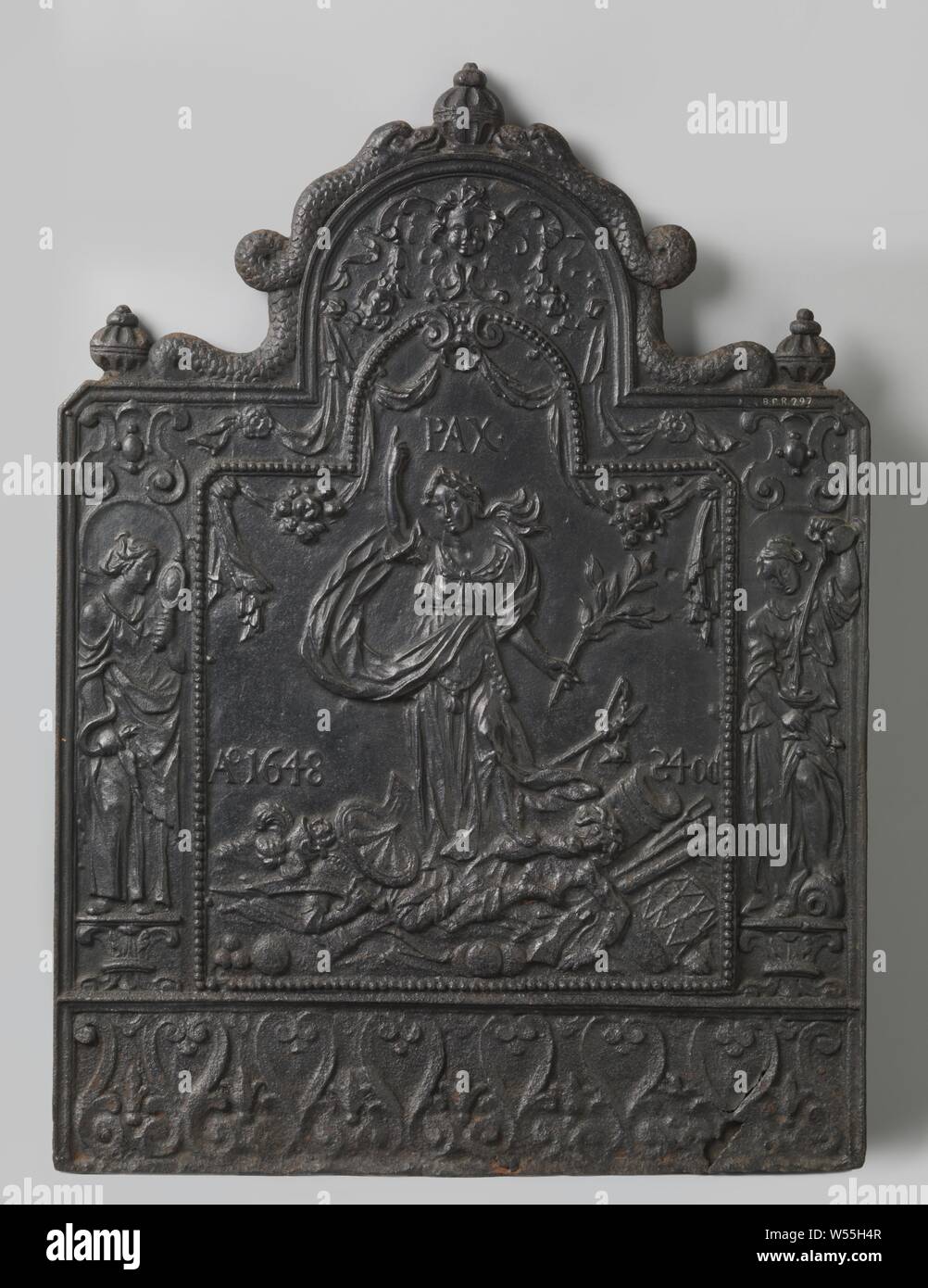 Fire plate with allegory on the Peace of Munster, Fire plate made of cast iron, with a semicircular top. Central is the personification of Peace with a palm branch in her hand, draped above her canvases and the inscription PAX. Peace is on weapons and two men. Immediately next to Peace the inscription Ao 1648 24OC. The whole is framed with a border, decorated with a pearl border and a virtue on either side: left Prudentia with mirror and snake in the hands, right Temperantia with tazza and jug. At the top an angel's head amidst fruits, at the bottom mirrored S-volutes. The top is crowned Stock Photo