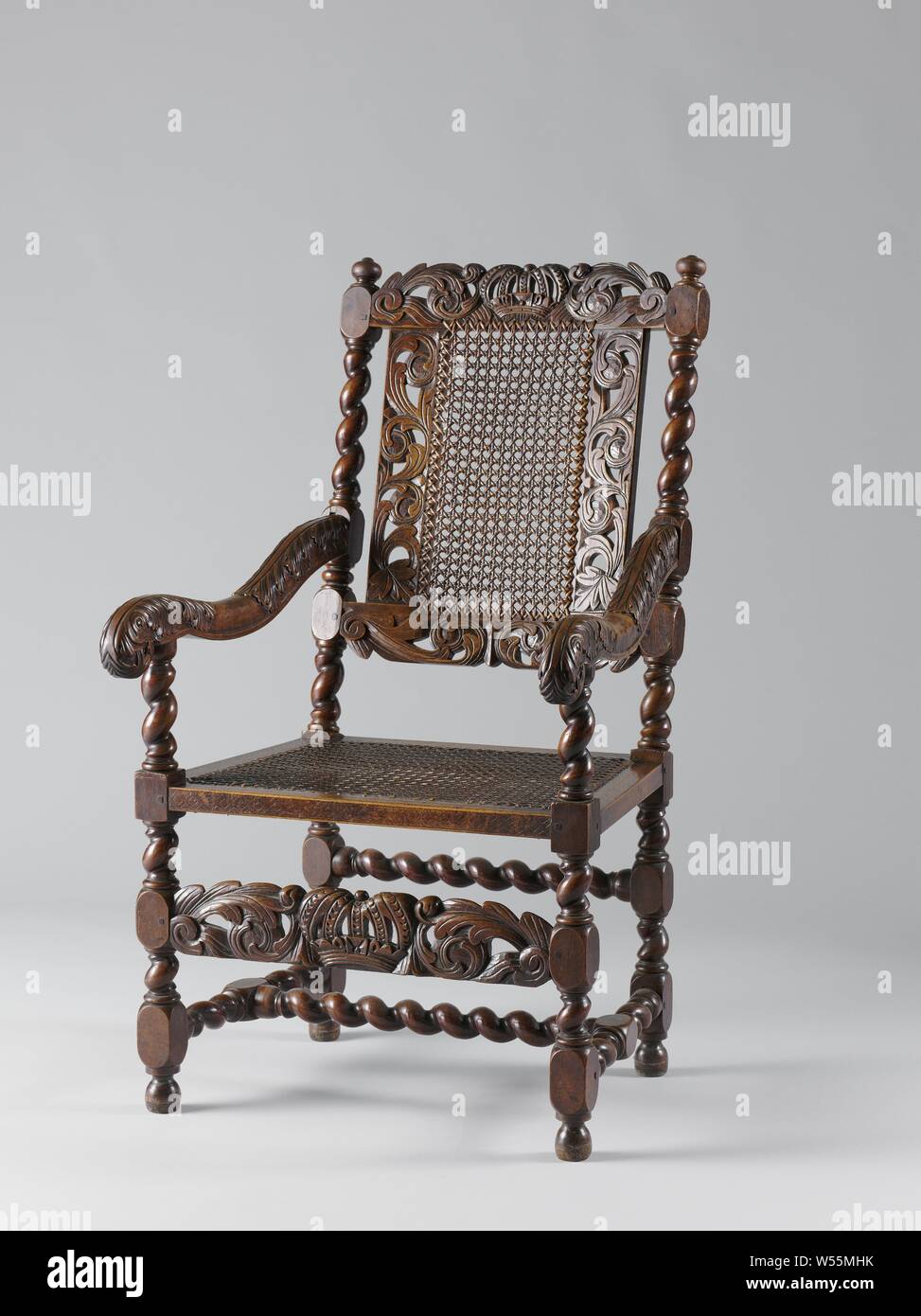 Armchair, covered with cane, back window and front cover cut open with acanthus curls with a royal crown in front cover and top line, Armchair made of walnut. The furniture is covered with reed and has hinged legs, which are connected by an H-shaped window. The armrests rest on slung armrest struts, are hollowed and end in a volute, decorated with acanthus leaves. The freestanding corner posts are hurled. The back window and the foreport show openwork acanthus curls with a royal crown in the middle in the upper line and in the front. A band of diamond braiding is engraved in the seat frame Stock Photo