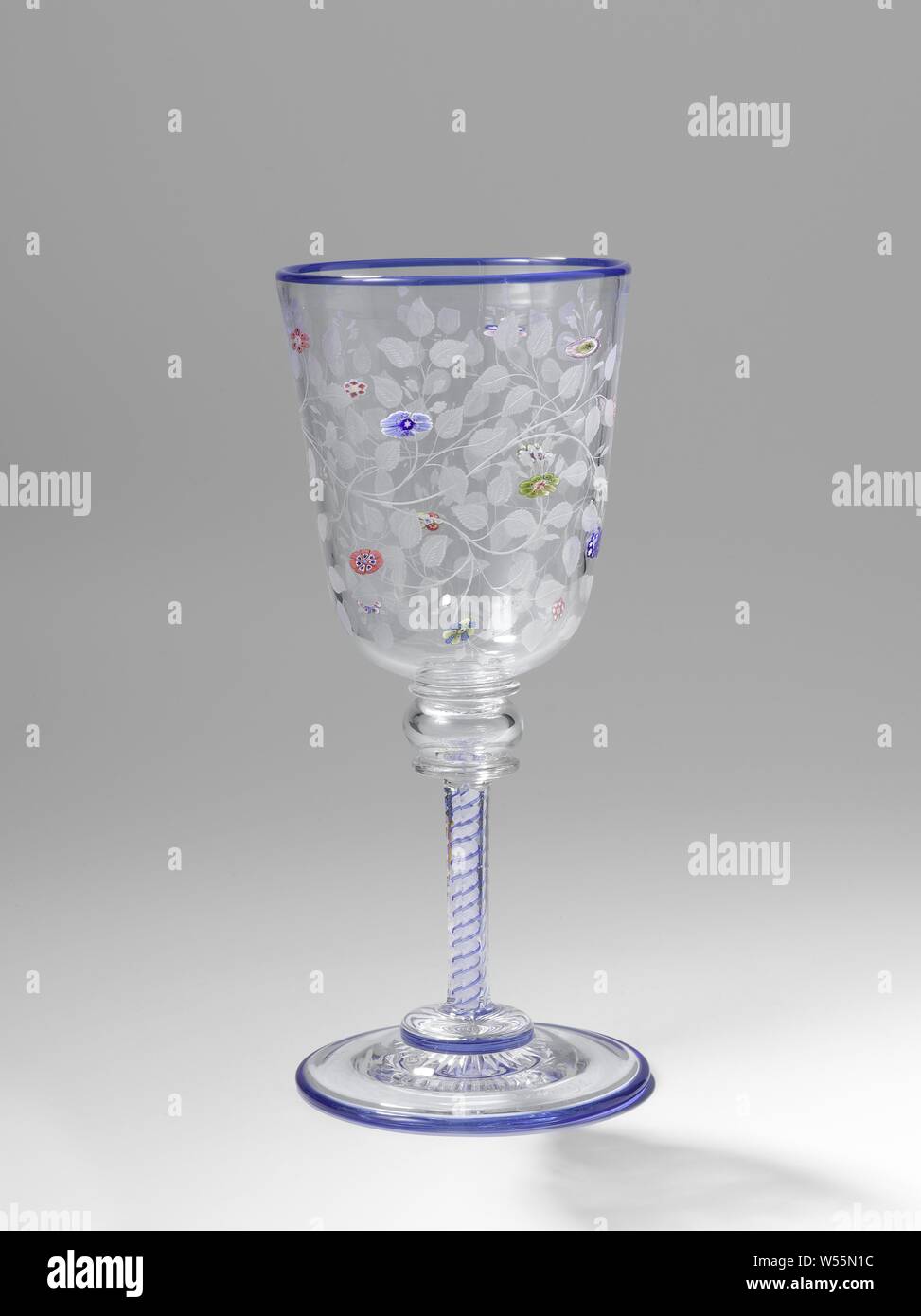 Wine glass Goblet with flower and leaf vines, Vaulted base with a ground star at the bottom. Faceted cut with a double white-blue spiral. Above that a hollow knot between two discs. Funnel shaped calyx, rounded on the underside, adorned with melted millefiori (flowers) in different colors of glass and with the wheel engraved vines, flowers, ornament, Baccarat, Paris, 1846 - c. 1860, glass, millefiori glass, grinding, h 20.3 cm × d 8.9 cm Stock Photo