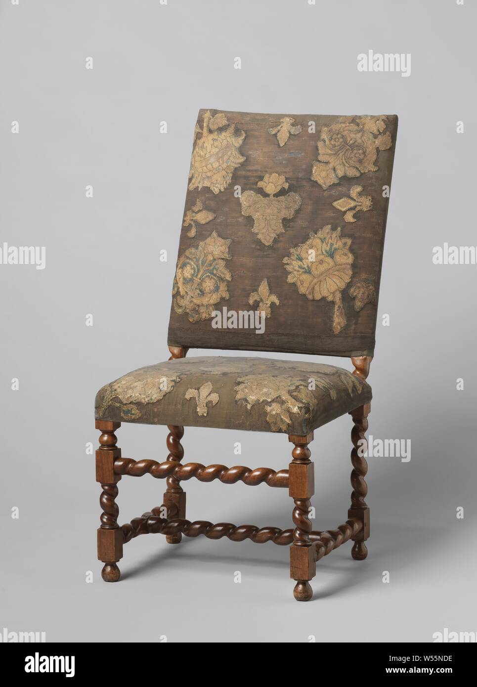 Furniture, Walnut chair covered with black velvet and tapestry sew-on. The furniture has slung legs, which are connected by an H-shaped cross and an upper sport, all also slung. The tapestry decoration on the upholstery shows flowers and lilies in green, salmon color, liver color and blue. The lining of the ridges is yellow damask. The webbing is old. One chair from a series of six, anonymous, Northern Netherlands, 1650 - 1700, wood (plant material), walnut (hardwood), velvet (fabric weave), damask, h 112 cm × w 56 cm × d 63.5 cm h 51 cm × w 56 cm × d 41 cm Stock Photo