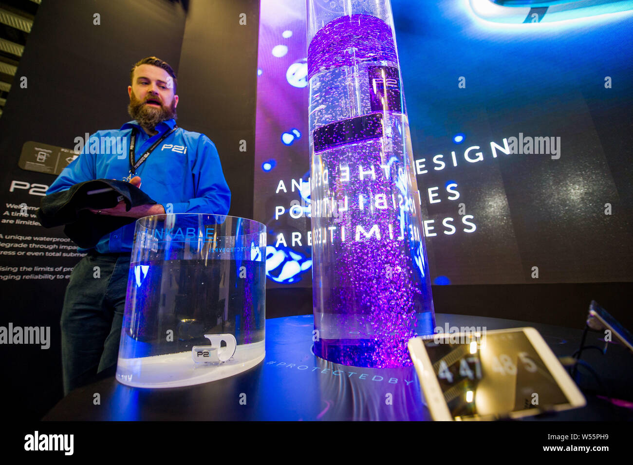 An employee of P2i introduces the company's water resistance technologies during the Mobile World Congress 2019 (MWC19) in Barcelona, Spain, 25 Februa Stock Photo
