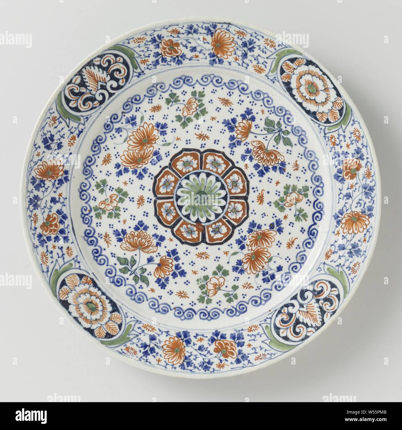 Plate with flower decorations and scatter flowers, Plate of earthenware, front and back covered with white tin glaze. Multicolored painting on the front with a rosette in green, red, black and blue on the flat and scattered flowers in red, green and blue. The border is decorated with four medallions in which a floral pattern in red, green and dark blue, with scattered flowers in between., anonymous, Delft, c. 1700 - c. 1725, d 22.0 cm × h 2.5 cm Stock Photo