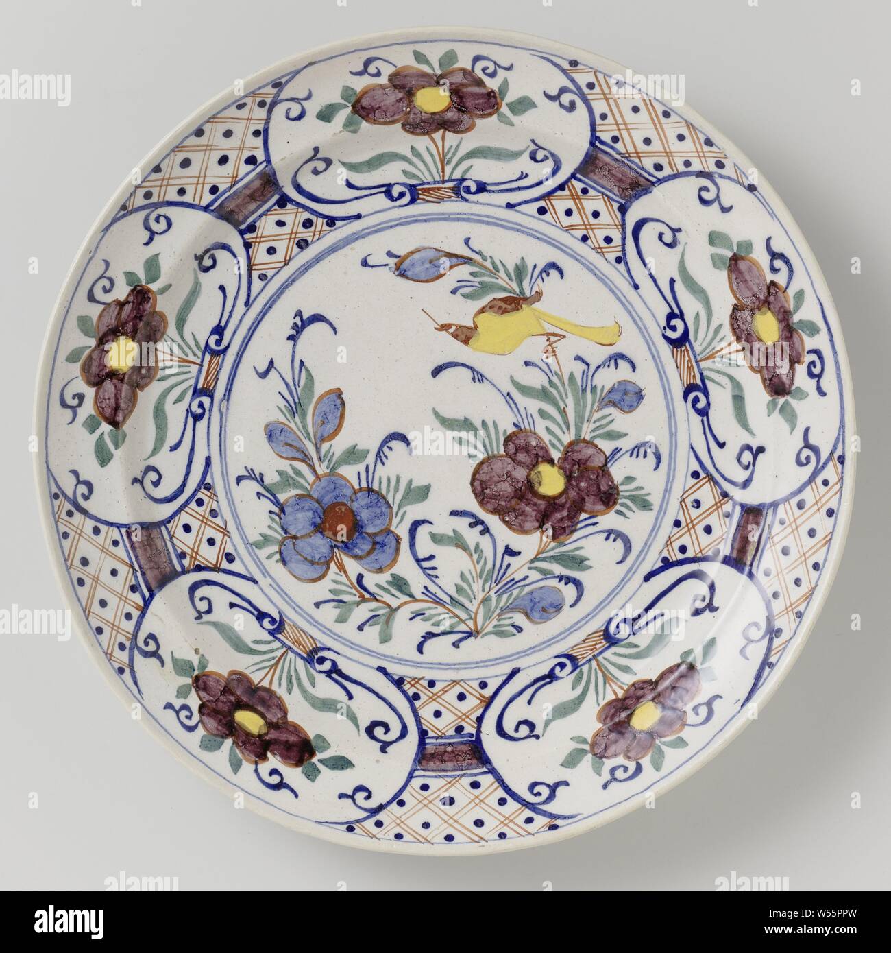 Dish, Round dish of multi-colored faience, with a circle on which a multi-colored bird and flowers are placed. A diamond pattern with dots is painted around the circle, in which five oval boxes with flowers in the colors yellow and manganese. The reverse side is marked with the number 5., anonymous, Delft, c. 1750 - c. 1780, earthenware, tin glaze, d 34.2 cm × h 5.4 cm Stock Photo