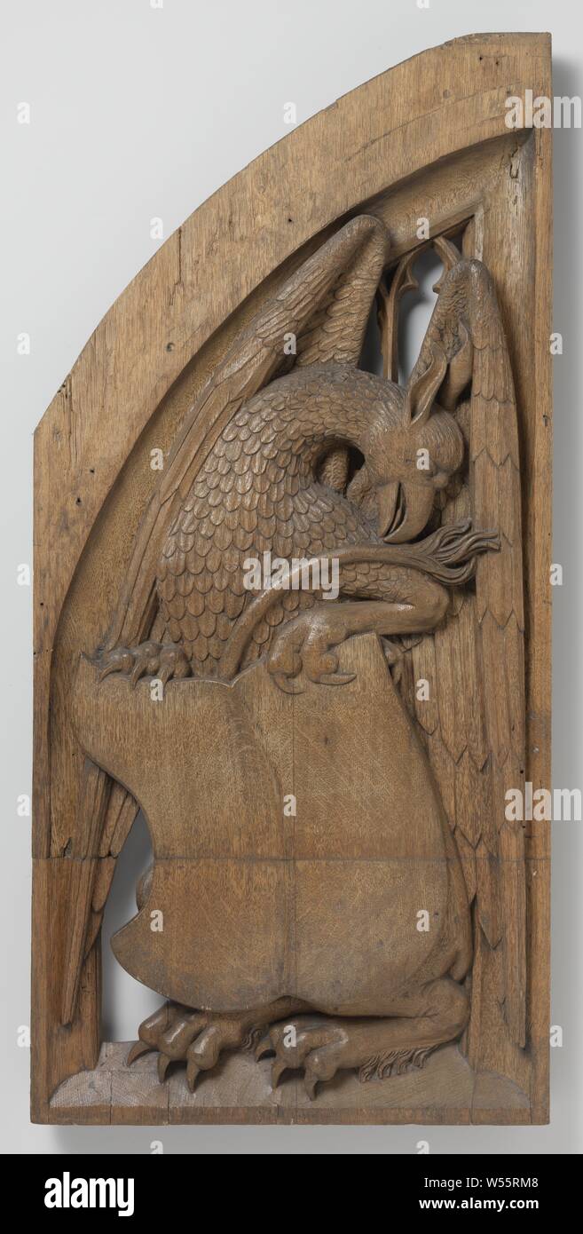 Panels from an organ case in the church of Saint Vitus in Naarden, Panel with a Griffin Supporting an Escutcheon, from the Organ case in St Vitus's Church, Naarden, A seated left-handed griffin with to the right the curved long neck and head. He holds the shield with both claws, above which his tail sticks out, the half-spread wings fill the background. The hatch has the shape of a half-pointed arch and has a concave frame that encloses tracery, griffin (lion / eagle), 'Griffo' (Ripa), Grote or Sint-Vituskerk, Jan Eerstensz. van Schayck, Utrecht, c. 1510 - c. 1520, oak (wood), h 88 cm × w 42 Stock Photo