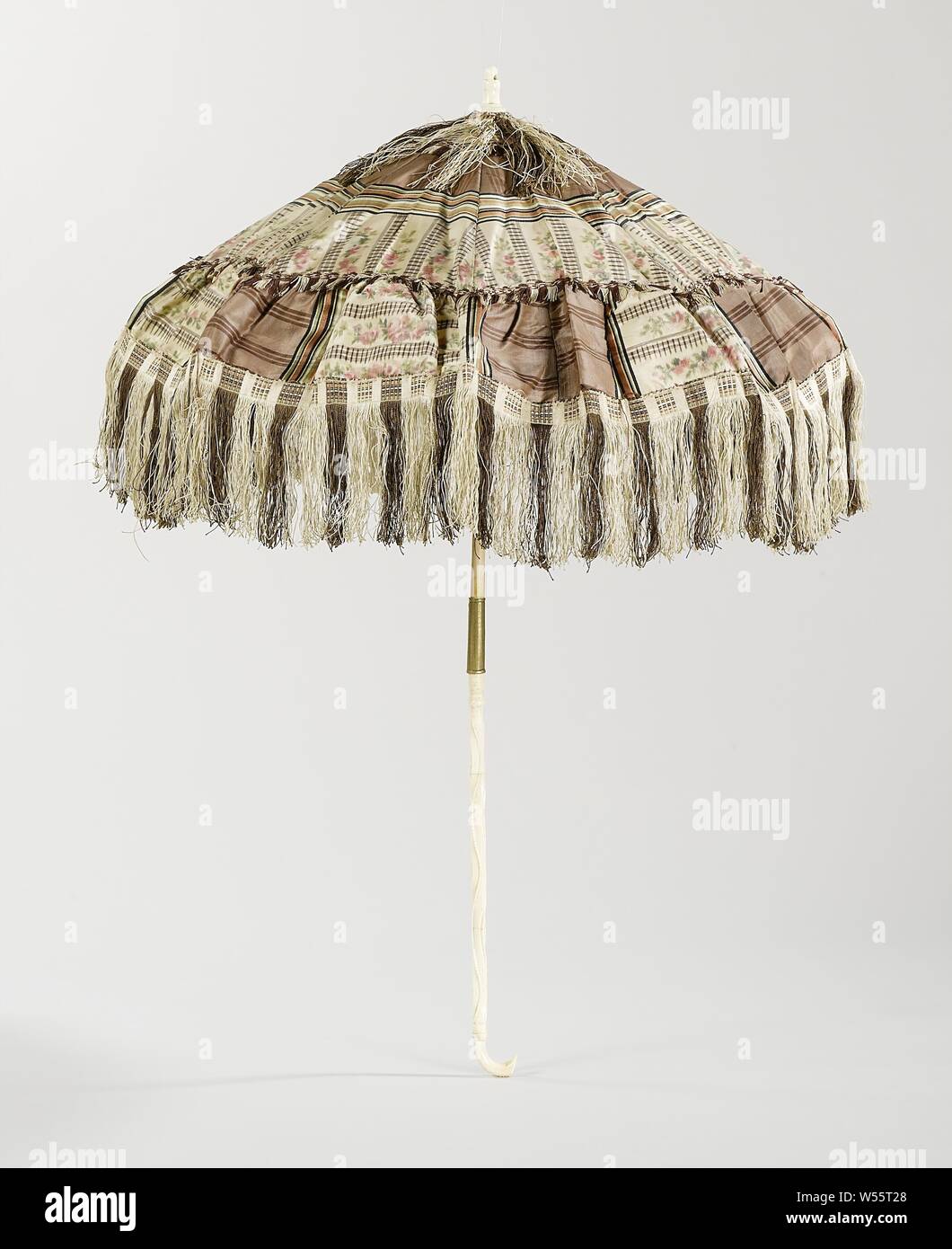 Carriage parasol Carriage parasol with silk-covered deck with brown stripes, interspersed with chiné pattern with rose garlands and gray cross stripes, handle made of wavy-cut leg, Carriage parasol with silk-covered deck with brown stripes, interspersed with chiné pattern with rose garlands and gray cross stripes. Along the edge a brown and white striped fringe. The parasol is lined with white ponjé silk, in which a border of fine, embossed flowers. Dark, wooden ribs. The handle is cut from bone with wave lines, two smoothly profiled and one toothed, with a small curved hook at the bottom Stock Photo