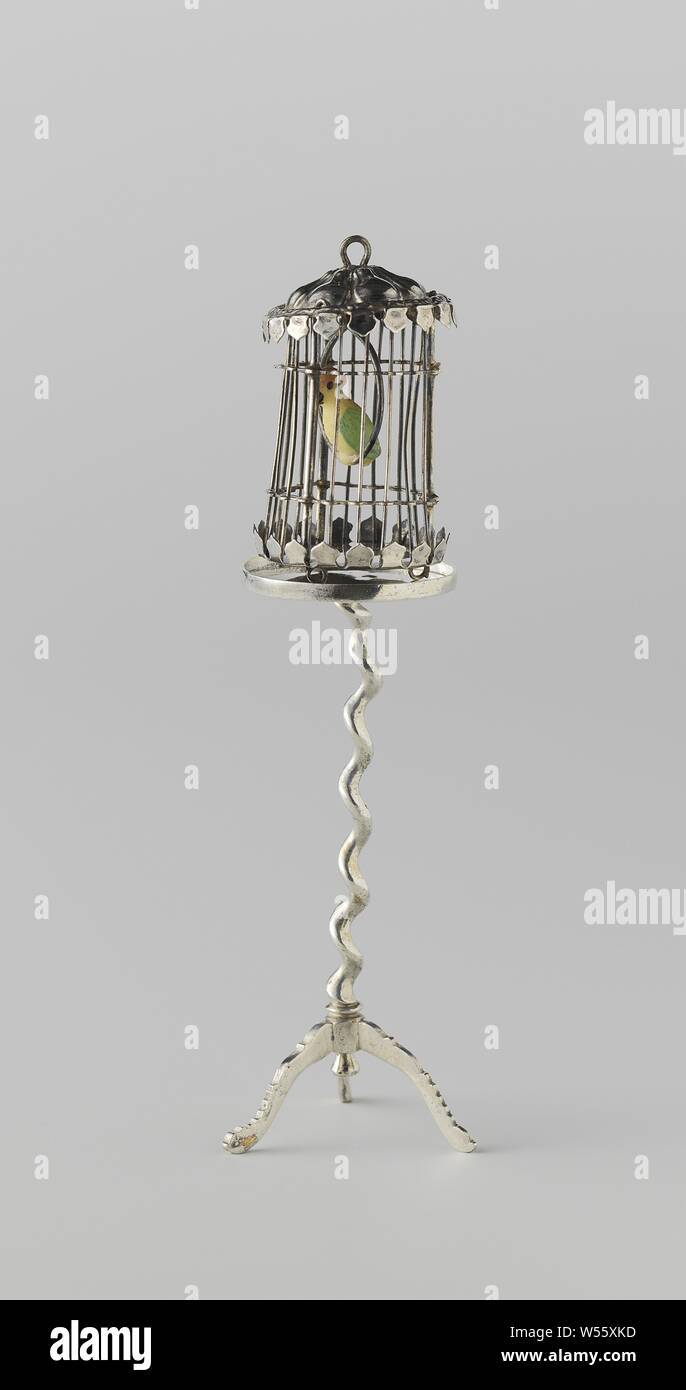 Birdcage with parrot, Round cylindrical birdcage. The top and bottom edges are like a lambbreaker. A colored bird is in a ring in the cage. The cage is on three rings and there is a support ring on top of the cage. The cage is marked: a boar's head and the number 13 (Hungarian hallmark). The cage stands on a gueridone, Bird in a cage, anonymous, Germany, c. 1870 - c. 1900, silver (metal), h 5.1 cm Stock Photo