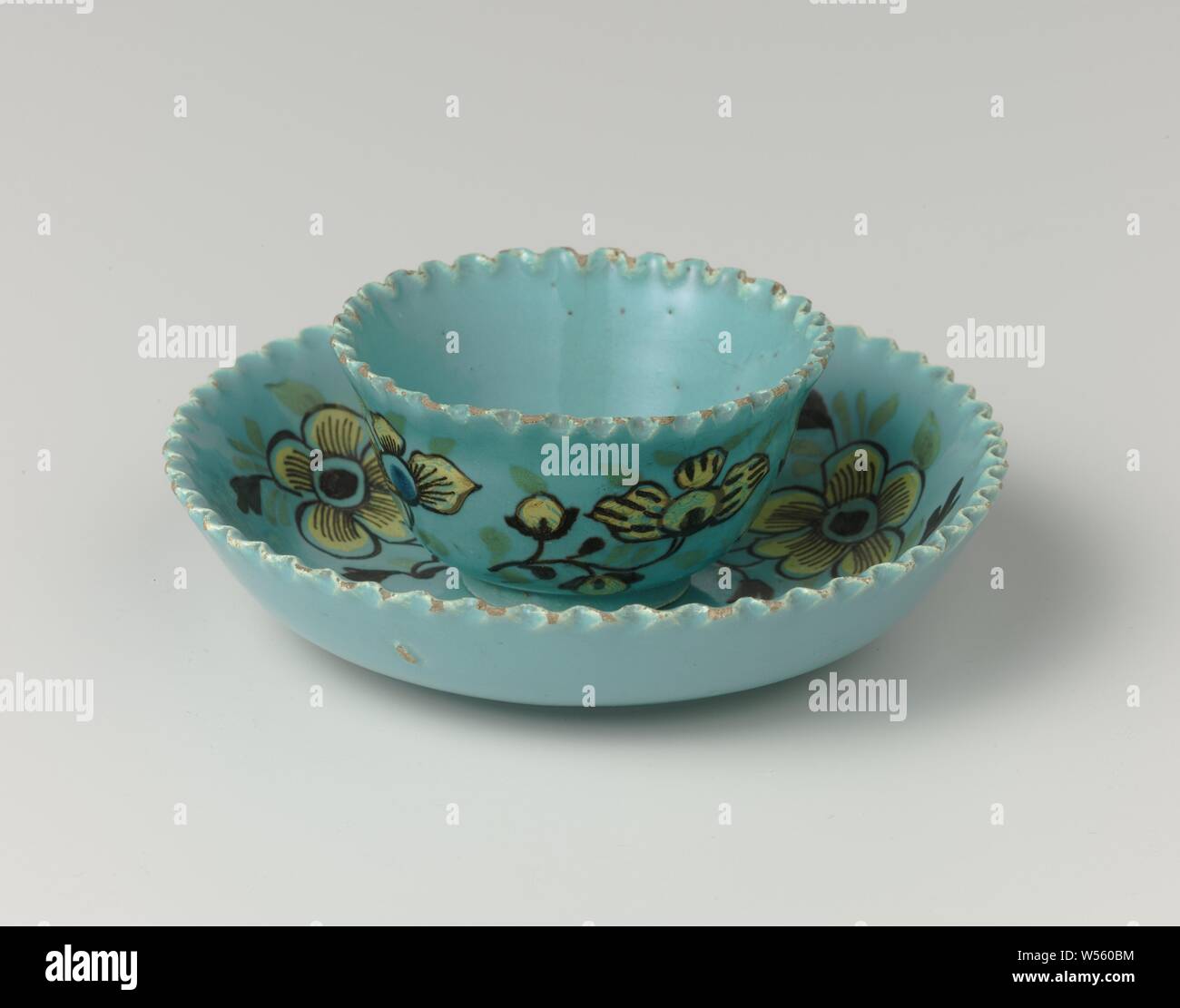 Dish, Dish of multi-colored faience. The cup and saucer are painted with yellow flowers on a turquoise background. The edges of the dish are serrated., anonymous, Delft, c. 1720 - c. 1750, earthenware, tin glaze, h 2.5 cm × d 11.0 cm Stock Photo
