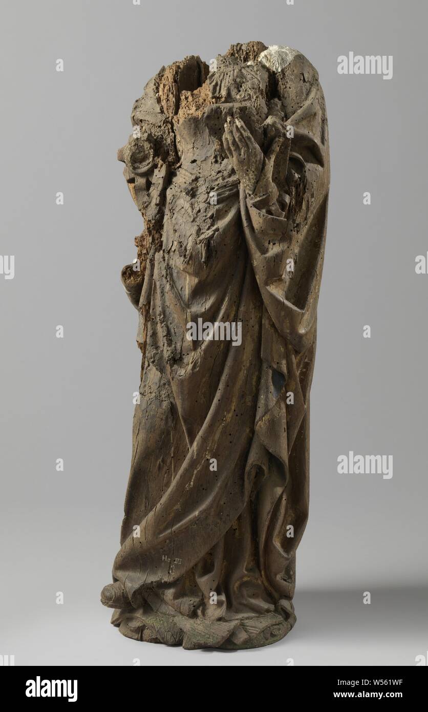 Female Saint (? St Agatha), She stands slightly forward with her right foot on a piece of land and holds a fragment of an open book in her left hand. Below the label with scalloped neckline and with sleeves, with slits, a thin pleated shirt. The cloak hangs from the shoulders and is included with the arms. The blunt right shoe point and part of undergarment under the skirt of the hall. A hanging sash for the waist. The head is missing., anonymous, Utrecht, c. 1500 - c. 1520, oak (wood), gilding, h 82 cm × w 34 cm × d 21 cm Stock Photo