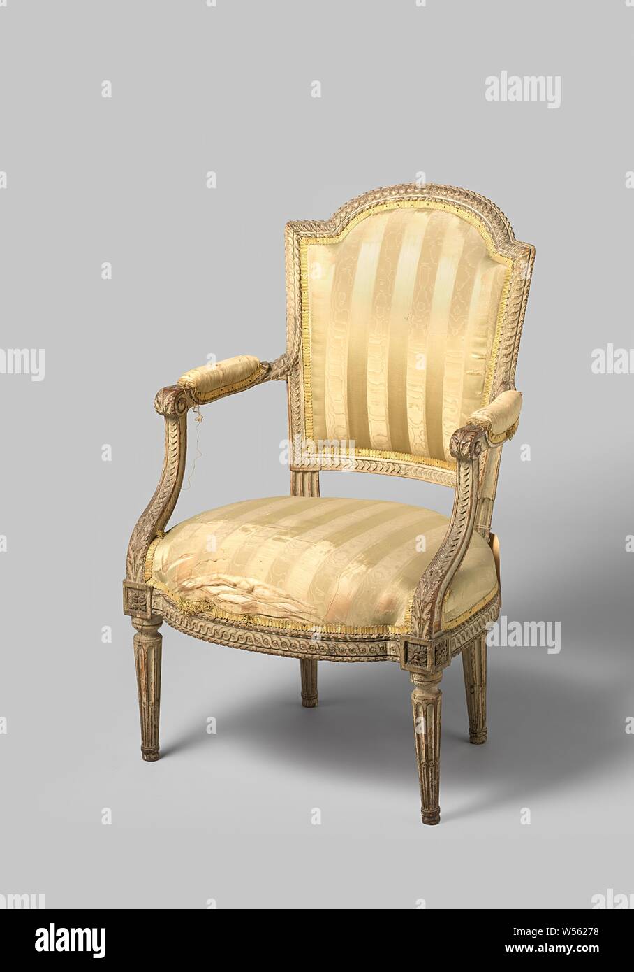 Armchair, upholstered in white painted beech, upholstered in white painted beech and resting on conical legs above which are square houses with rosettes. The seat lines, armrests and struts and the seat frame have a stitched braid band, between an ornament of ribbon hurled around a bar. The square armrest struts with acanthus leaf recede to the rear. The armrests with cushions end in a volute and merge into the trapezoidal hollowed back frame. The back window rests on fluted struts and has a scalloped upper sill., anonymous, France, 1775 - 1800, wood (plant material), beech (wood), textile Stock Photo
