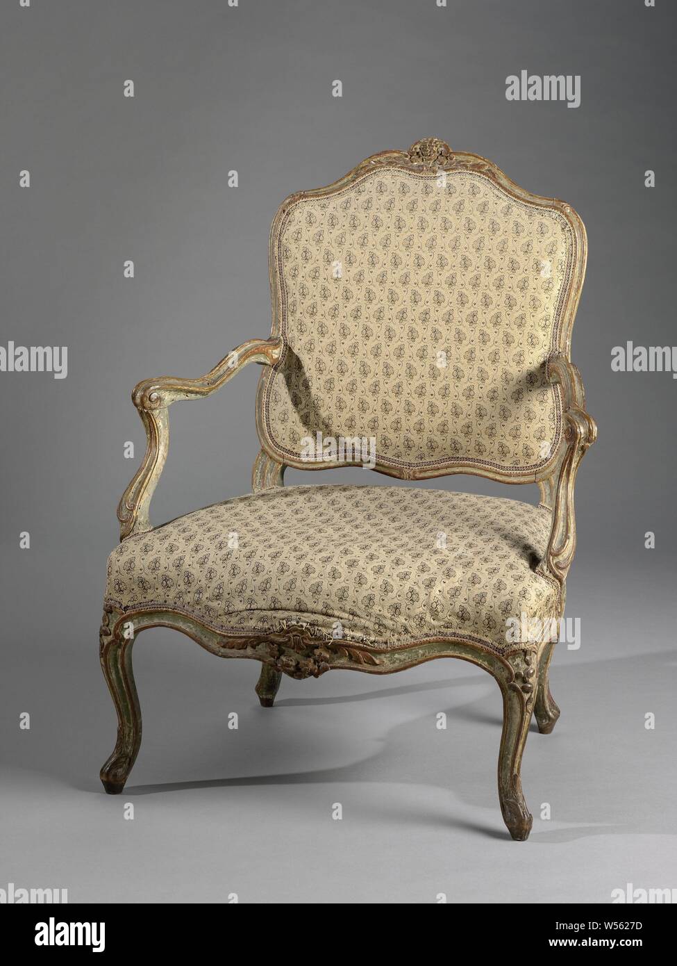 Armchair made of beech wood, upholstered and painted light green and gold. The S-shaped legs placed at an angle transcend to the scalloped seating lines. Several parts carry carved decorations. The struts and hollowed armrests are stretched S-shaped, the struts run in a continuous movement backwards, from the seat to the armrests that move outwards. The propped back frame is scalloped on the top and sides. Contour enhanced by profile tires with volutes. Marked on the inside-back., S. Canot, France, 1750, wood (plant material), beech (wood), textile materials, paint (coating), h 96, × w 72 cm Stock Photo