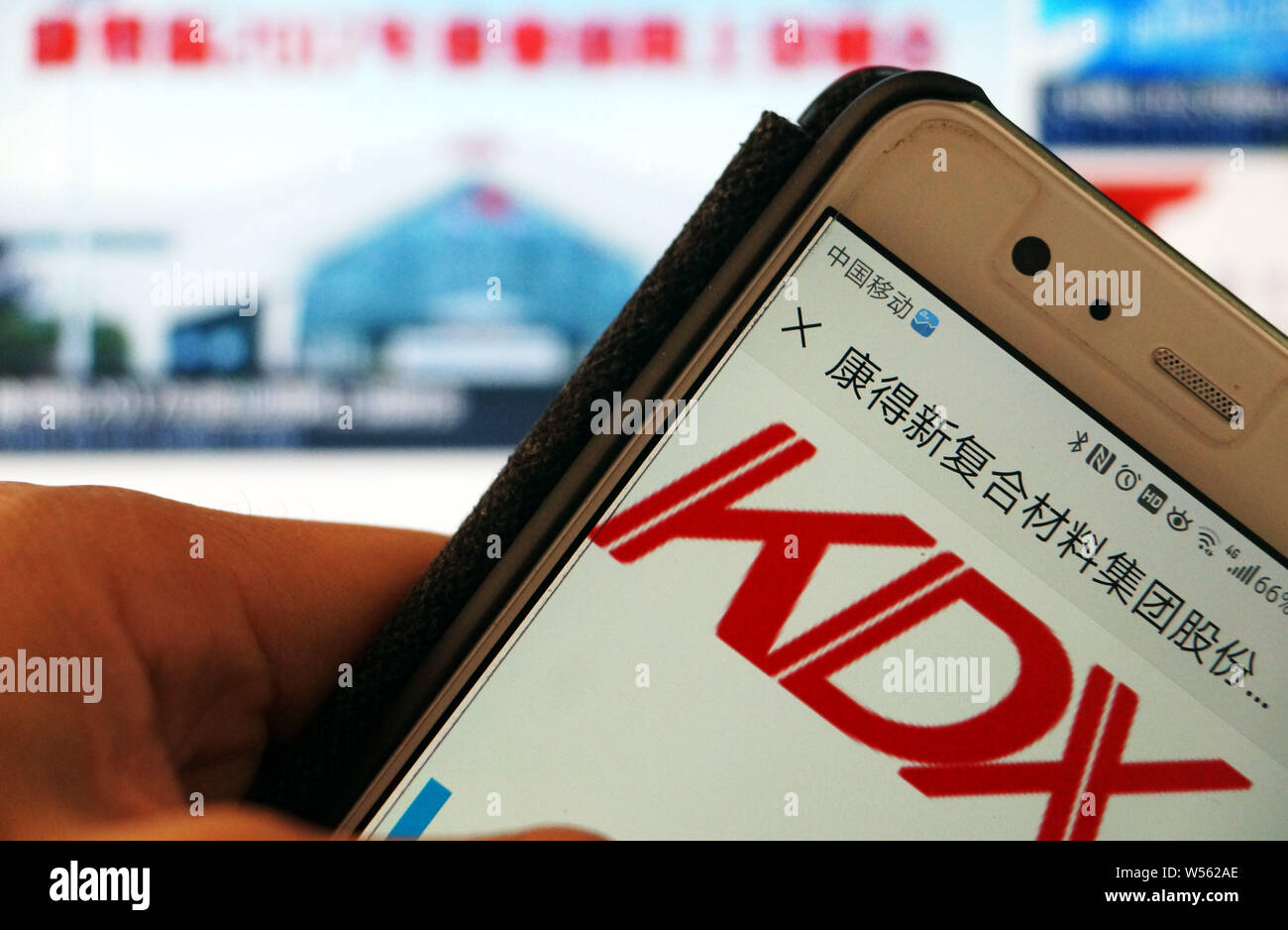 --FILE--A Chinese mobile phone user looks at a logo of Shenzhen-listed Kangdexin Composite Material Group Co. Ltd. on his smartphone in Tianjin, China Stock Photo