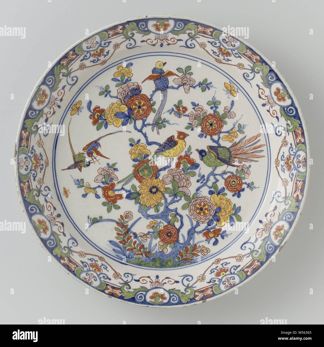 Saucer, multicolored painted with Chinoiserie, Faience saucer, multicolored painted with Chinoiserie: on the shelf a flower with birds. Edge of lambrequins., anonymous, Delft, c. 1715 - c. 1740, d 34.7 cm × h 4.8 cm Stock Photo