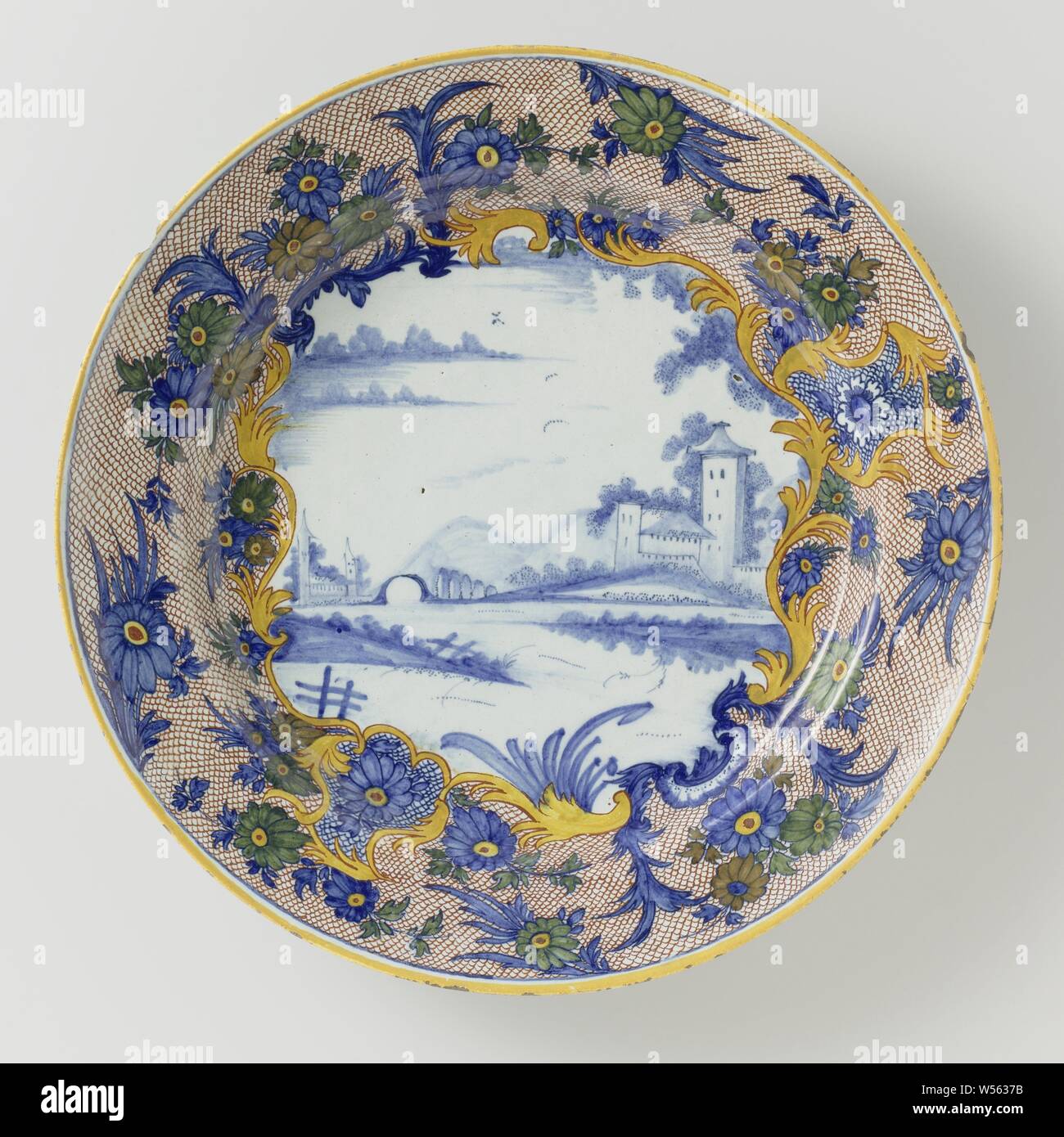 Dish of multicolored painted faience, Dish of faience. On the shelf a landscape in blue. Around it a multicolored flower border., anonymous, Delft, c. 1750 - c. 1780, d 34.8 cm × h 5.7 cm Stock Photo