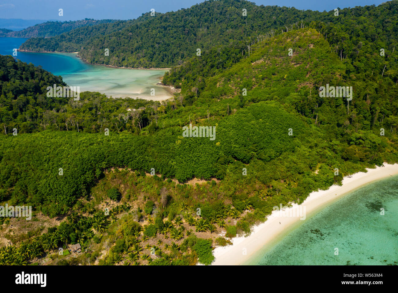Aerial drone view of a small fishing village on a lush, green tropical island Stock Photo