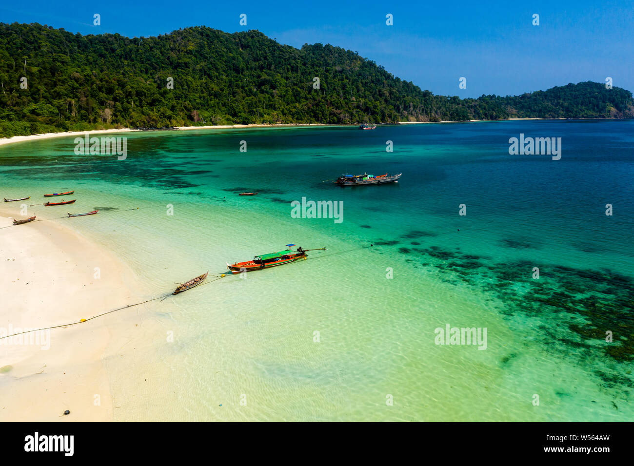 Aerial drone view of longtail fishing boats next to a beach of a small tropical island Stock Photo