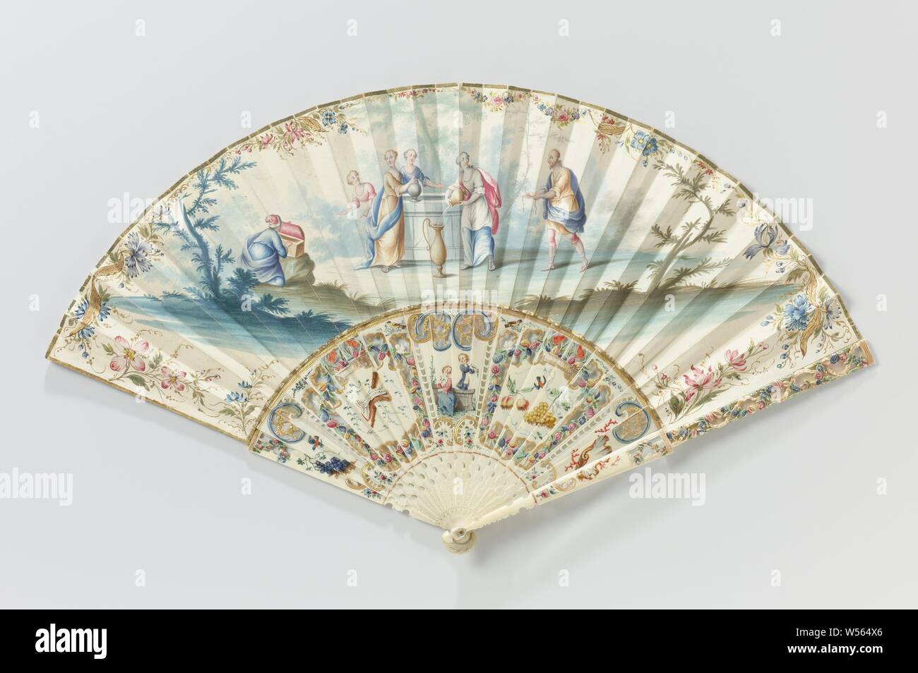 Folding fan with leaf on which in watercolor Eliezer, Rebecca at the source, on a frame of carved and painted ivory with mother-of-pearl, On the leaf is an episode from the much loved Bible story about bridal recruitment and marriage van Isaac, which was frequently depicted on fan blades. The most commonly used - similarly here - was the moment when Eliezer handed over the jewelry and thus made the actual proposal (Gen. 24:22). This is not surprising, since many of these fans were intended as a wedding gift. Eliezer was sent by Abraham to the city of Nahor to find a bride for his son Isaac Stock Photo
