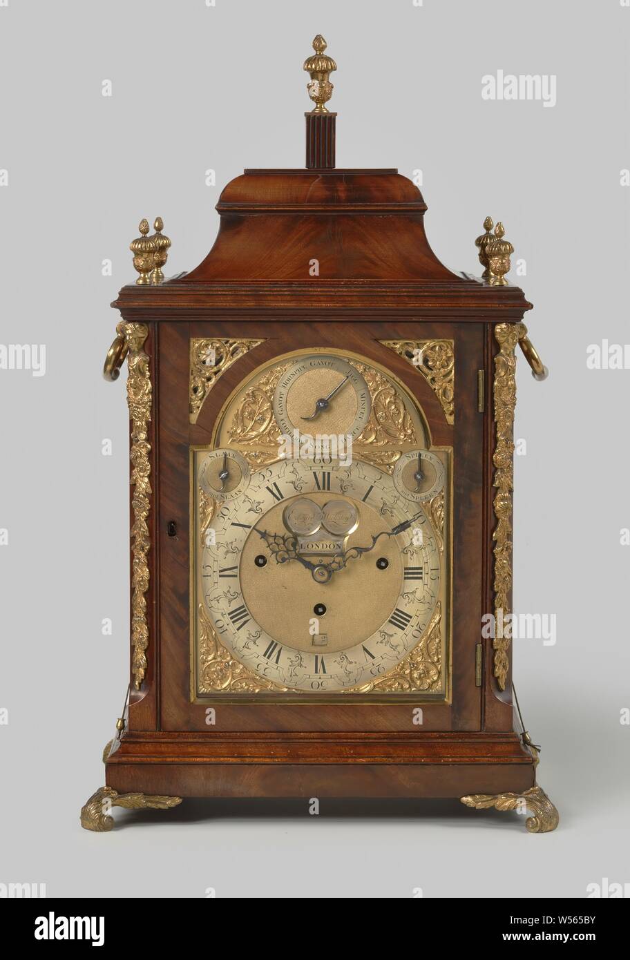 Table clock with percussion and playing, Table clock with percussion and playing. Case of mahogany, decorated with gold-plated copper. Dial and work are marked: EDWARD WICKSTEED.LONDON. The following roles have been put into the music roll: Gavot, Jigg, Minuet, Dance, Song, Cotillon, Gavot, Hornpipe., Edward Wicksteed, London, 1840 - 1860, mahogany (wood), brass (alloy), bronze (metal), gilding, h 63.5 cm × w 38.5 cm × d 26.5 cm Stock Photo
